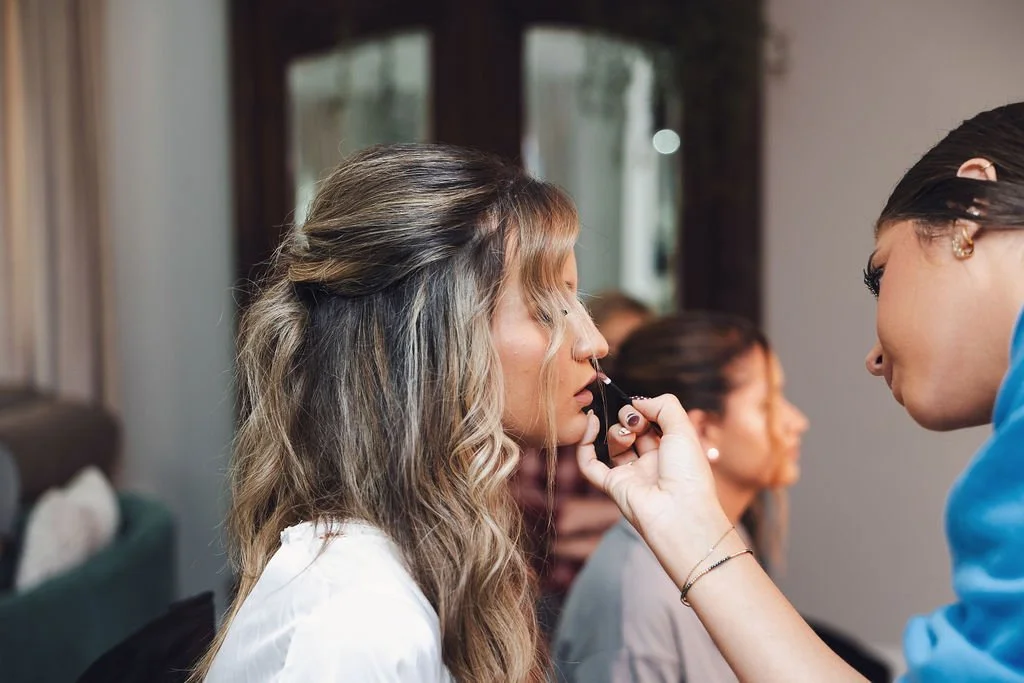 Makeup artist applying lip color to a bride during wedding morning beauty preparations