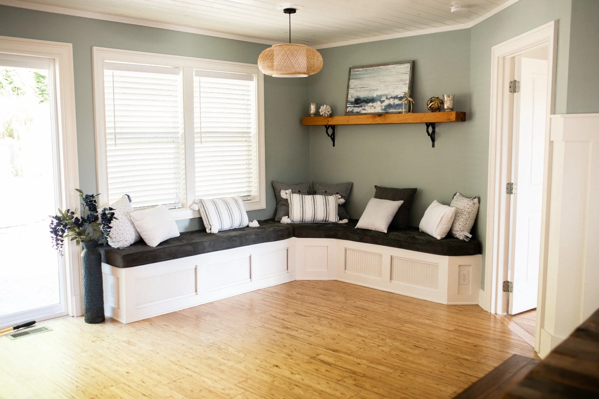 Cozy window seat lounge at the Manor onsite accommodation at Ramble Creek, featuring built-in bench seating, soft pillows, sage green walls, and warm wood floors.