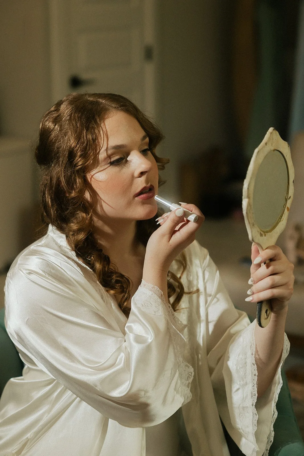Bride applying lipstick in Ramble Creek Bridal Suite, photography by Sun Reigh