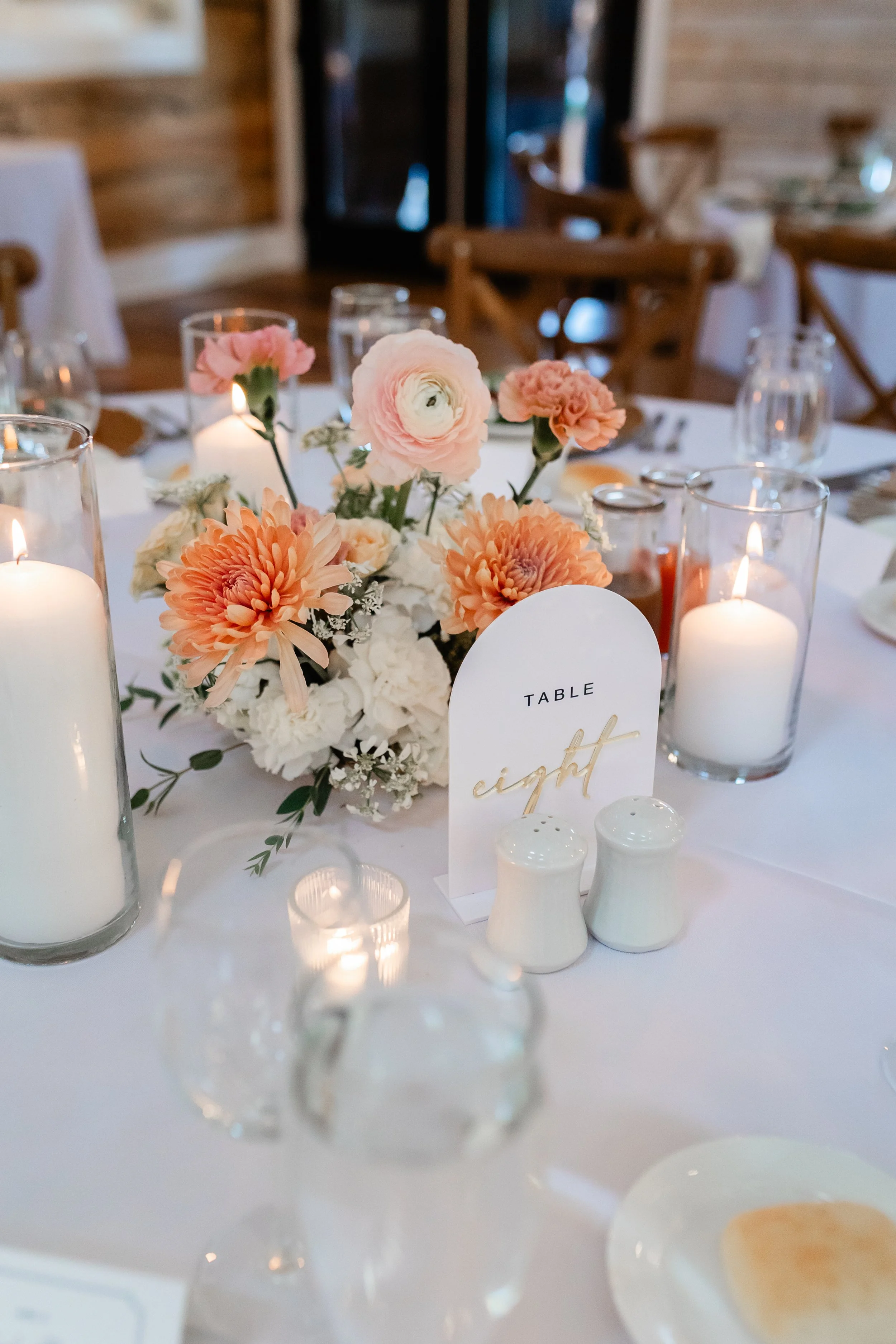 Table eight wedding reception centerpiece at Ramble Creek Wedding Venue in Tennessee with peach and white flowers, candlelight, and elegant place settings.