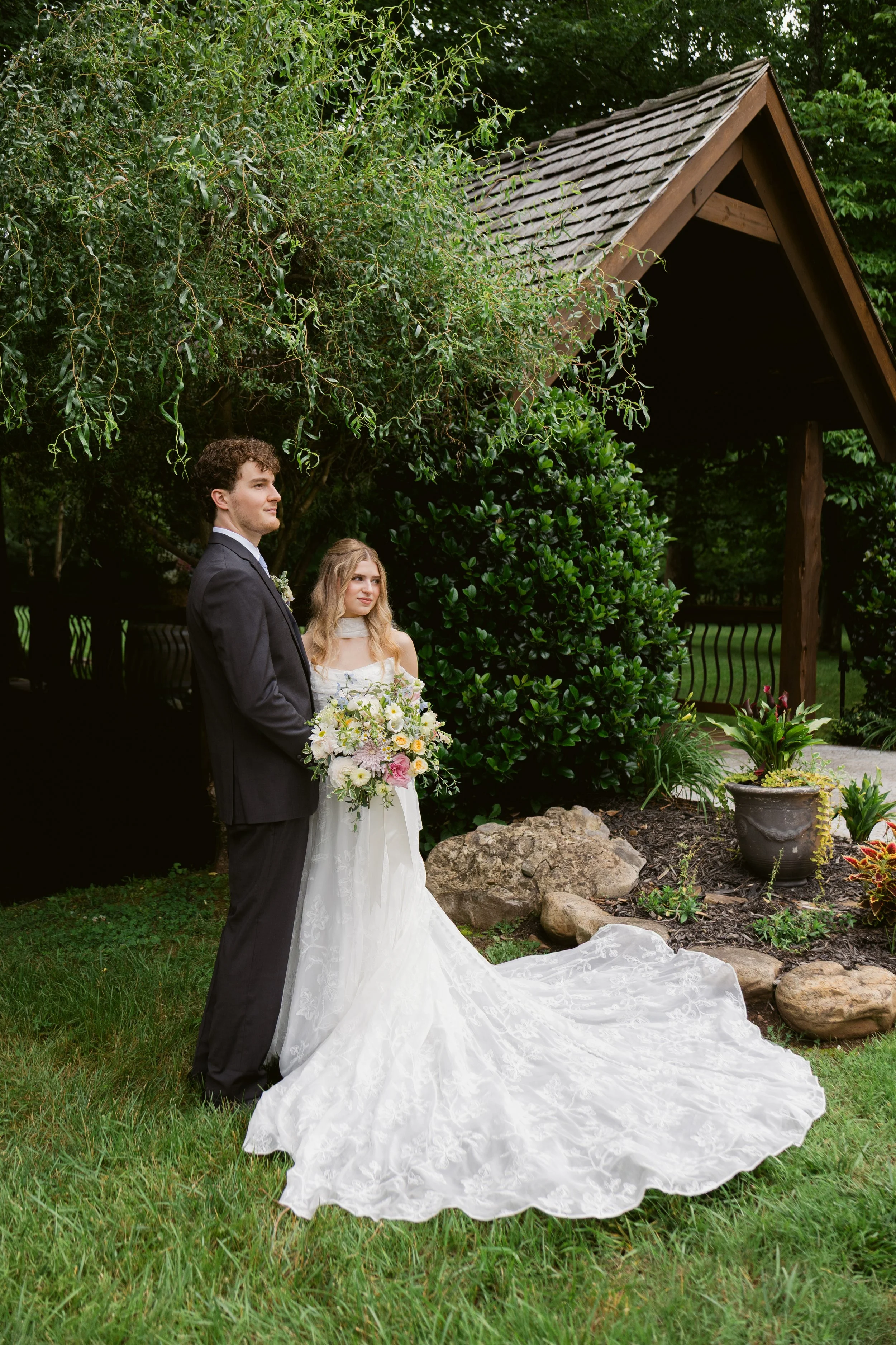 Bride and groom portrait by Ramble Creek’s covered bridge, surrounded by lush summer greenery at the Tennessee wedding venue.