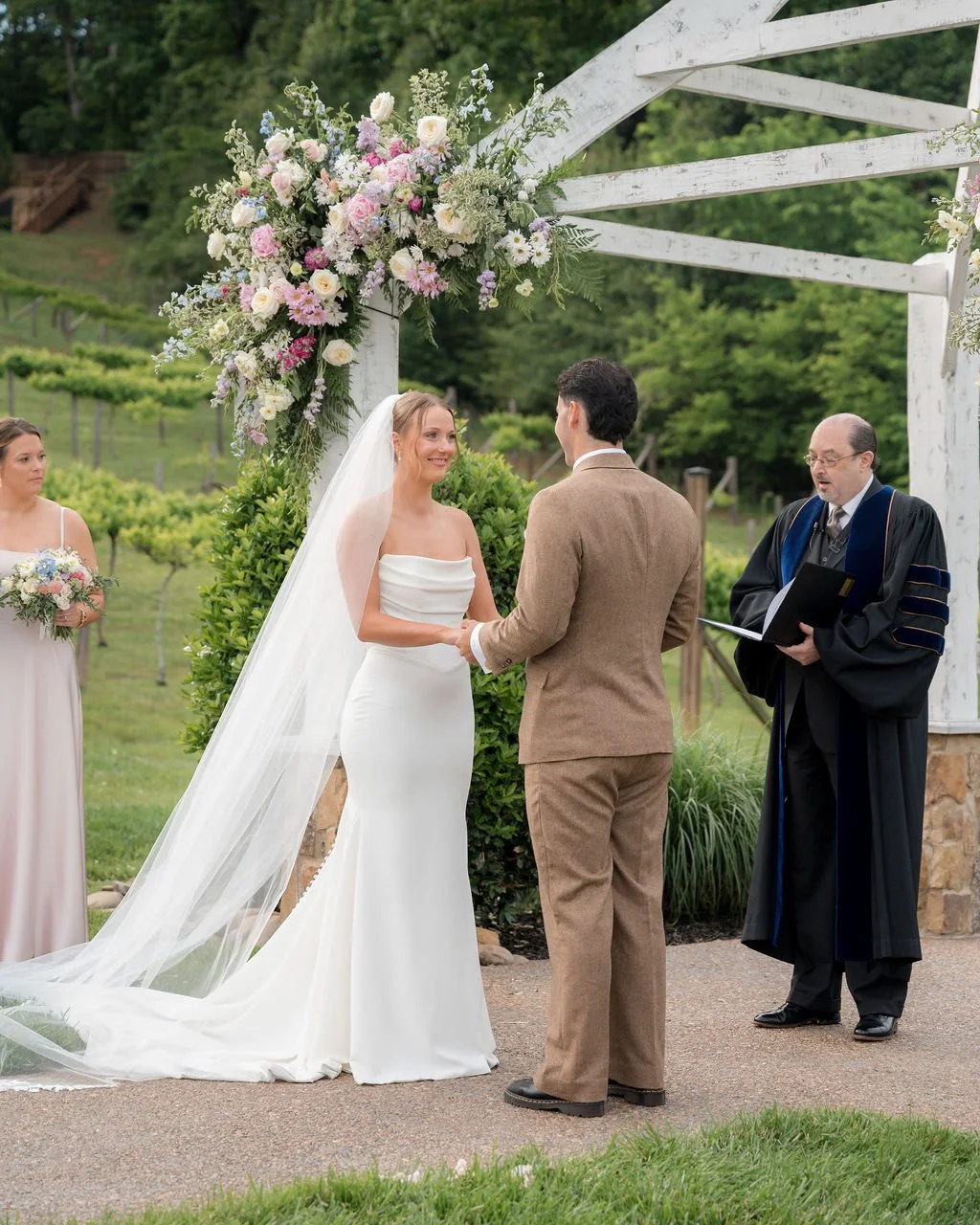 Bride and groom exchanging vows beneath a floral arbor on Ramble Creek’s upper lawn during a spring wedding ceremony in Tennessee.
