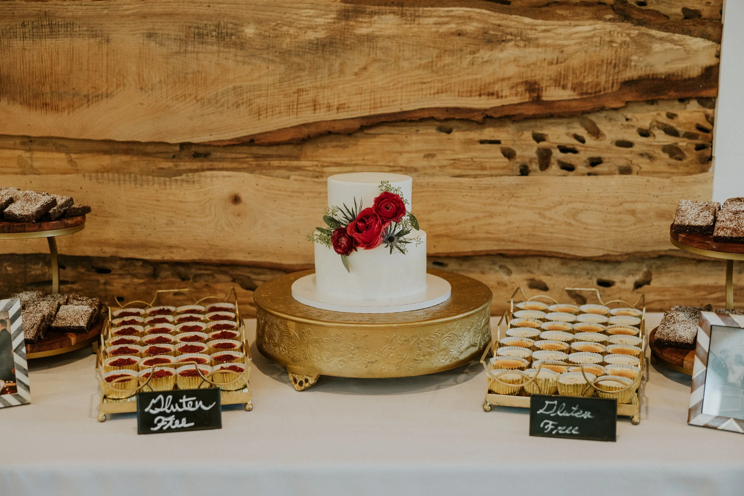 Wedding cake with red floral accents displayed with gluten-free dessert options at Ramble Creek, a Tennessee wedding venue with rustic, luxurious wood reception details