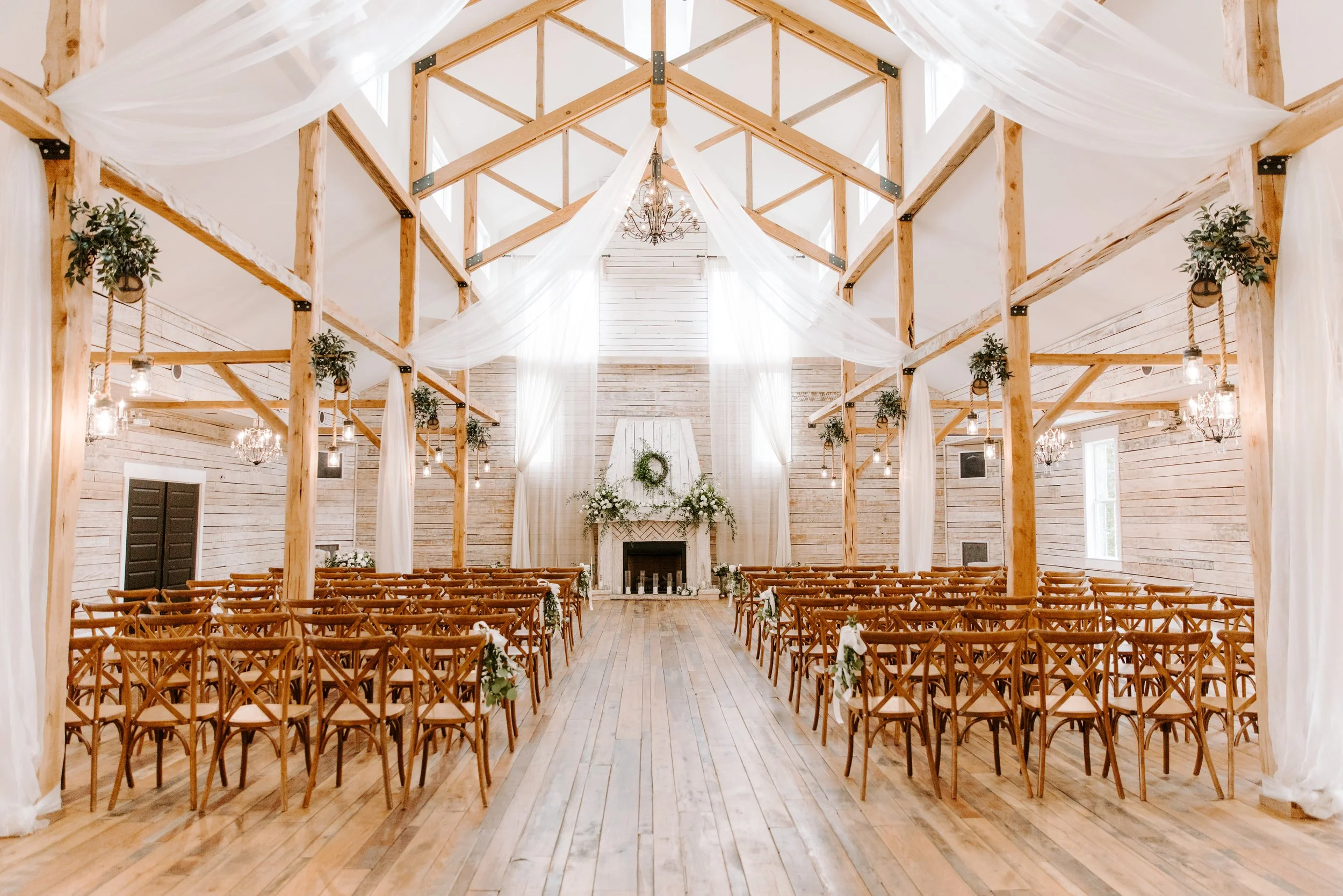 Light-filled Grand Hall with wooden beams, draped fabric, and ceremony seating at Ramble Creek indoor wedding venue in Tennessee