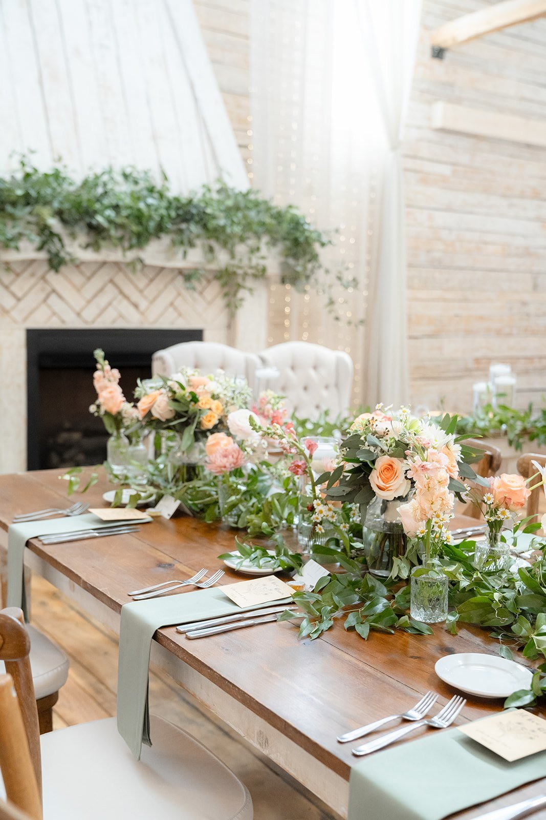 Elegant wedding reception tablescape with pastel floral centerpieces, greenery runners, and candlelight decor styled on a rustic wooden reception table at a Tennessee wedding venue, showcasing Ramble Creek in-house floral skills