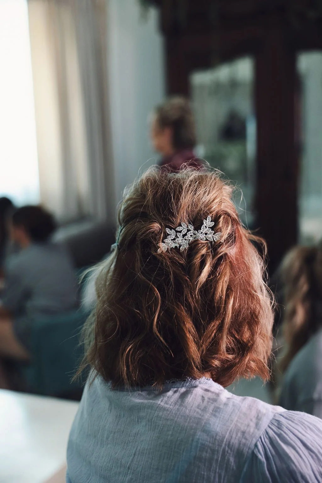 Back view of a mother-of-the-bride hairstyle with a delicate crystal hairpiece tucked into softly styled short hair