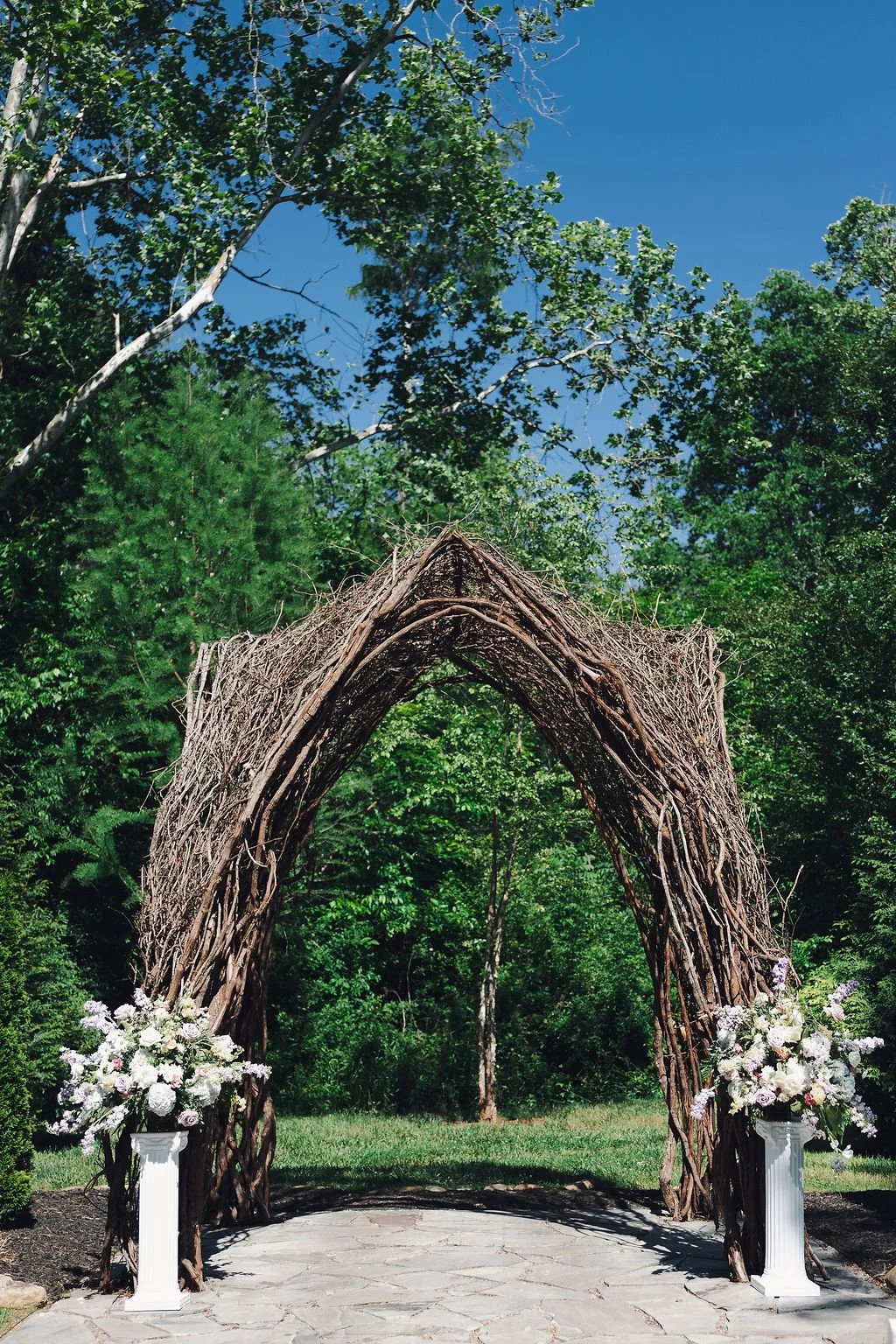 Natural vine arbor with white and lavender florals for an outdoor spring wedding ceremony at Ramble Creek in Tennessee.