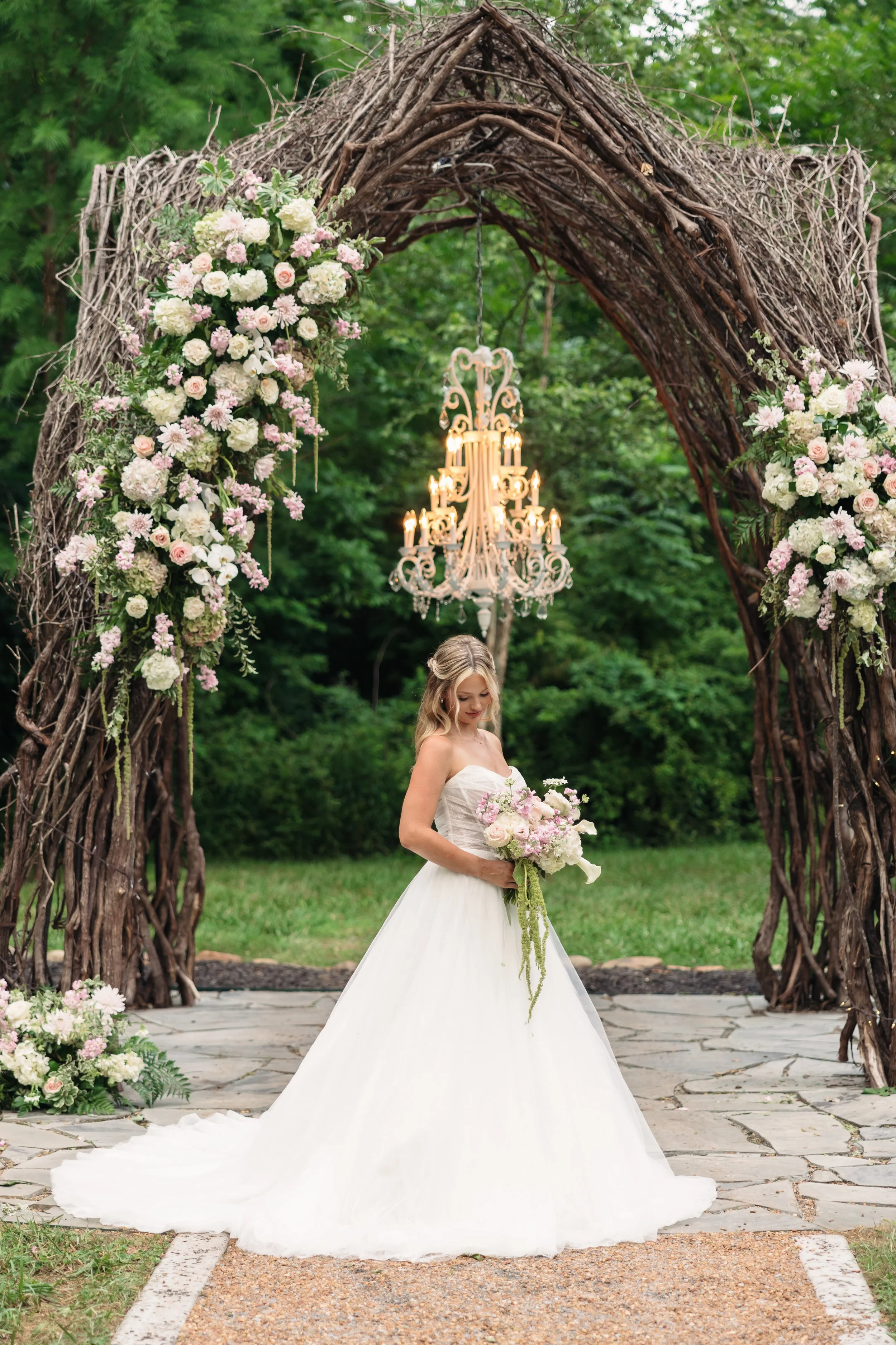 Bride holding a pastel bouquet beneath the outdoor floral ceremony arch at Ramble Creek Wedding Venue in Tennessee