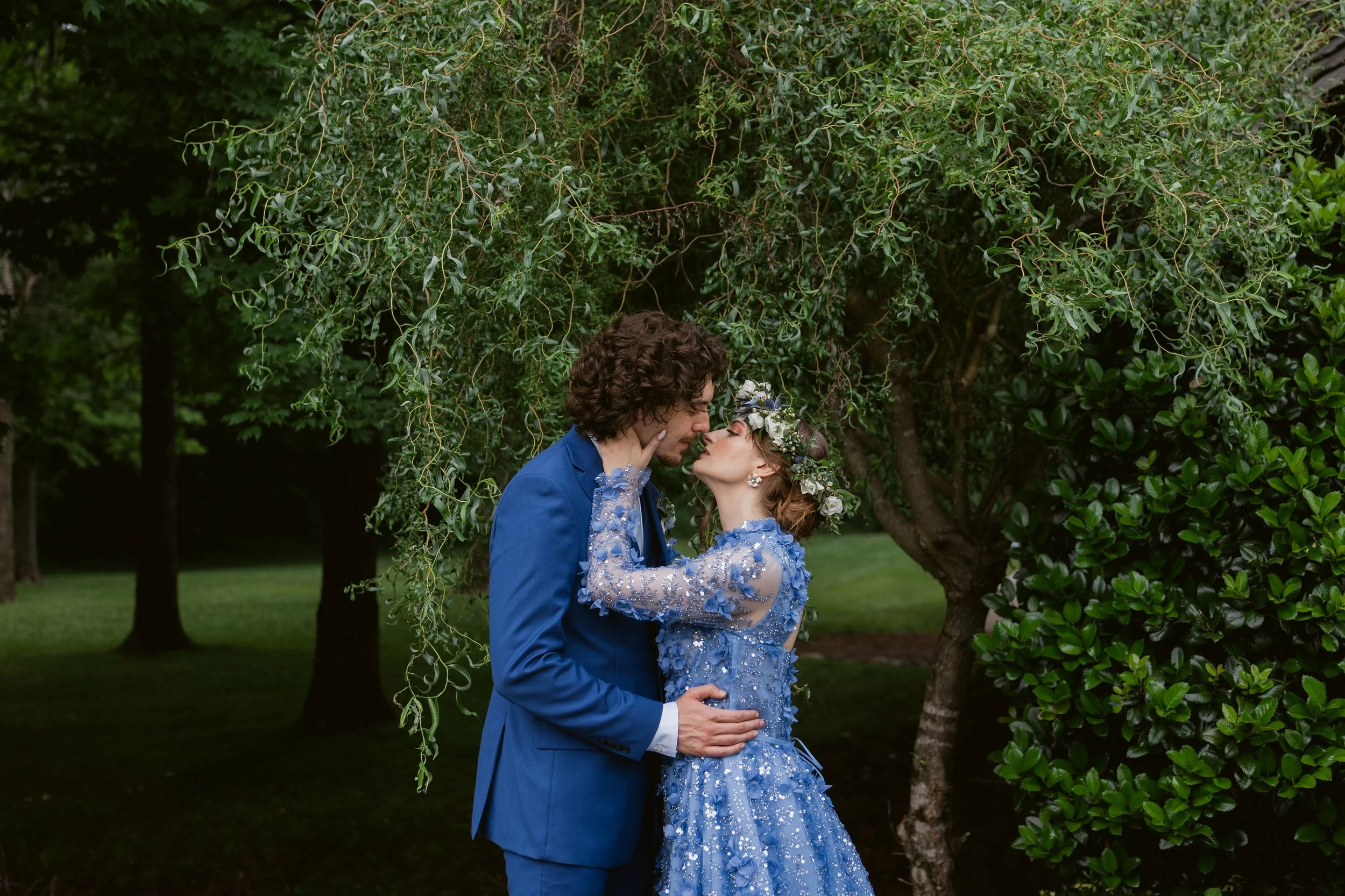 Bride in a blue floral wedding dress and groom in a blue suit sharing a romantic outdoor portrait at Ramble Creek, an all-inclusive East Tennessee wedding venue in Athens TN.