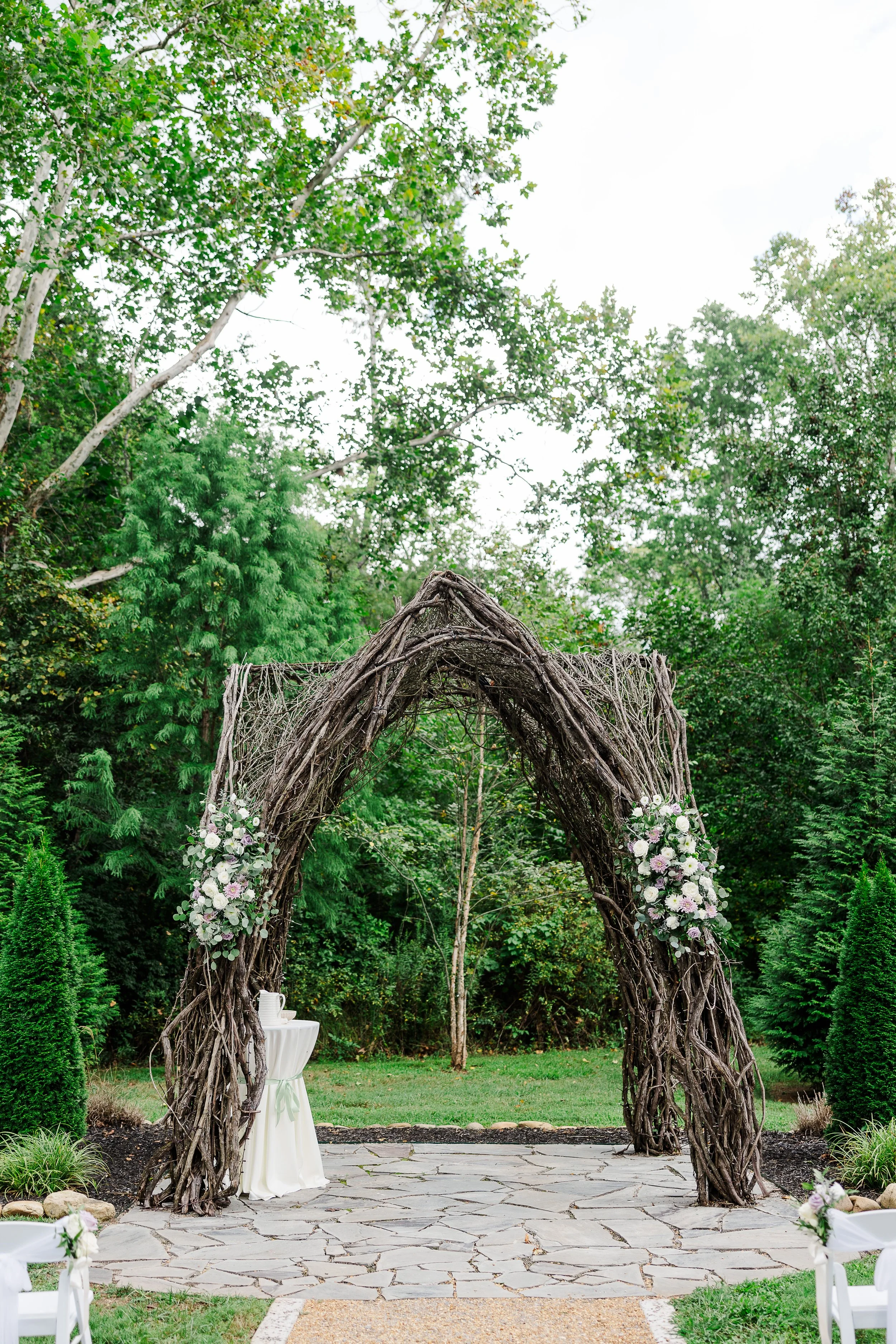 Outdoor ceremony space at Ramble Creek with a natural vine arbor, soft floral arrangements, and lush greenery for a romantic Tennessee summer wedding.