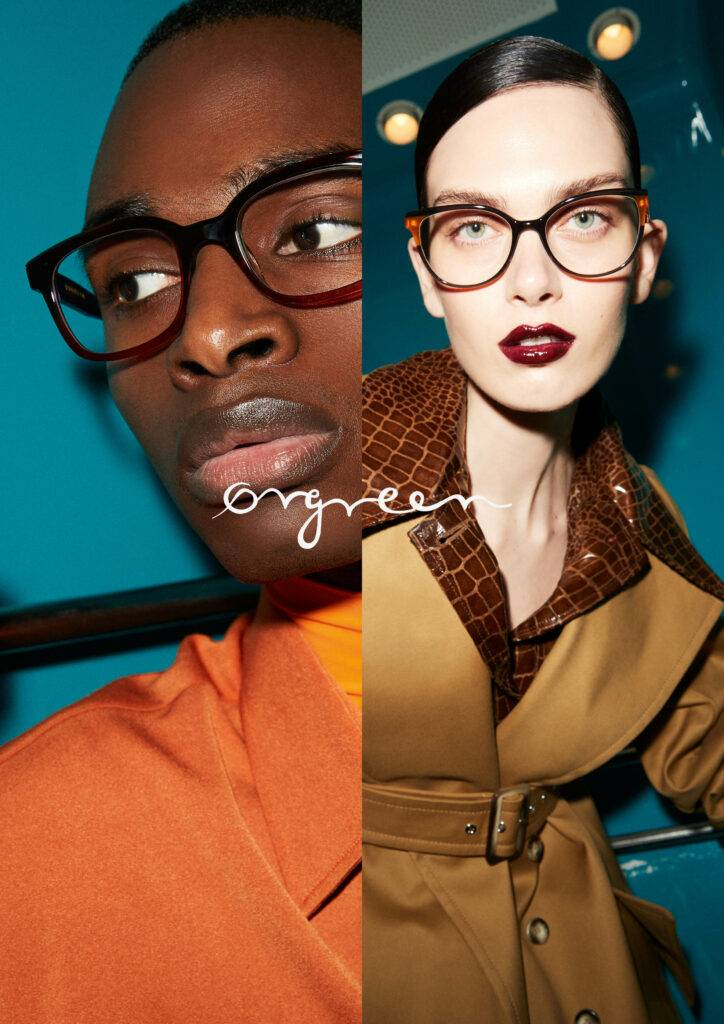Side-by-side portrait of two women wearing glasses with the word "oxygen" written across the center. The woman on the left has dark skin, short hair, and is wearing an orange top, while the woman on the right has light skin, dark hair, and is wearing a tan coat with a textured brown collar.
