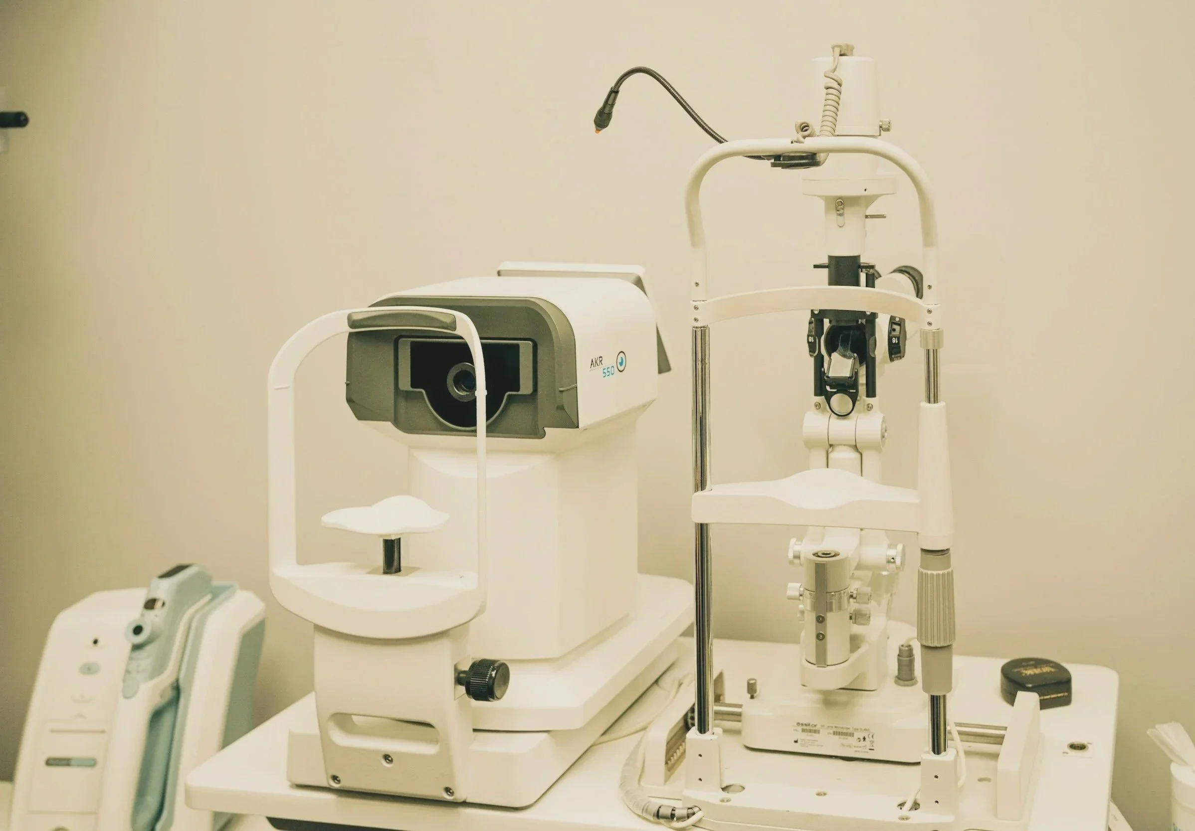 Optometrist equipment typically used for eye examinations, including a slit lamp and a camera, in a clinical setting.