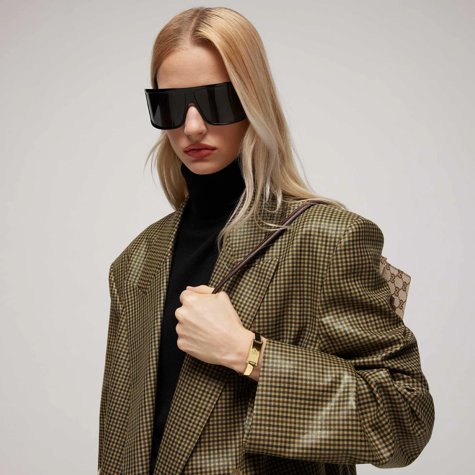 Woman wearing Gucci sunglasses, blazer, and Gucci handbag