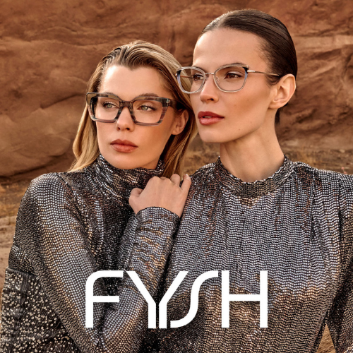 Two women wearing glasses and matching silver sequined tops standing outdoors with a rocky background, posing for a photo.