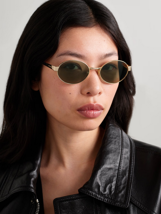 Woman with long dark hair wearing Saint Laurent sunglasses and a black leather jacket
