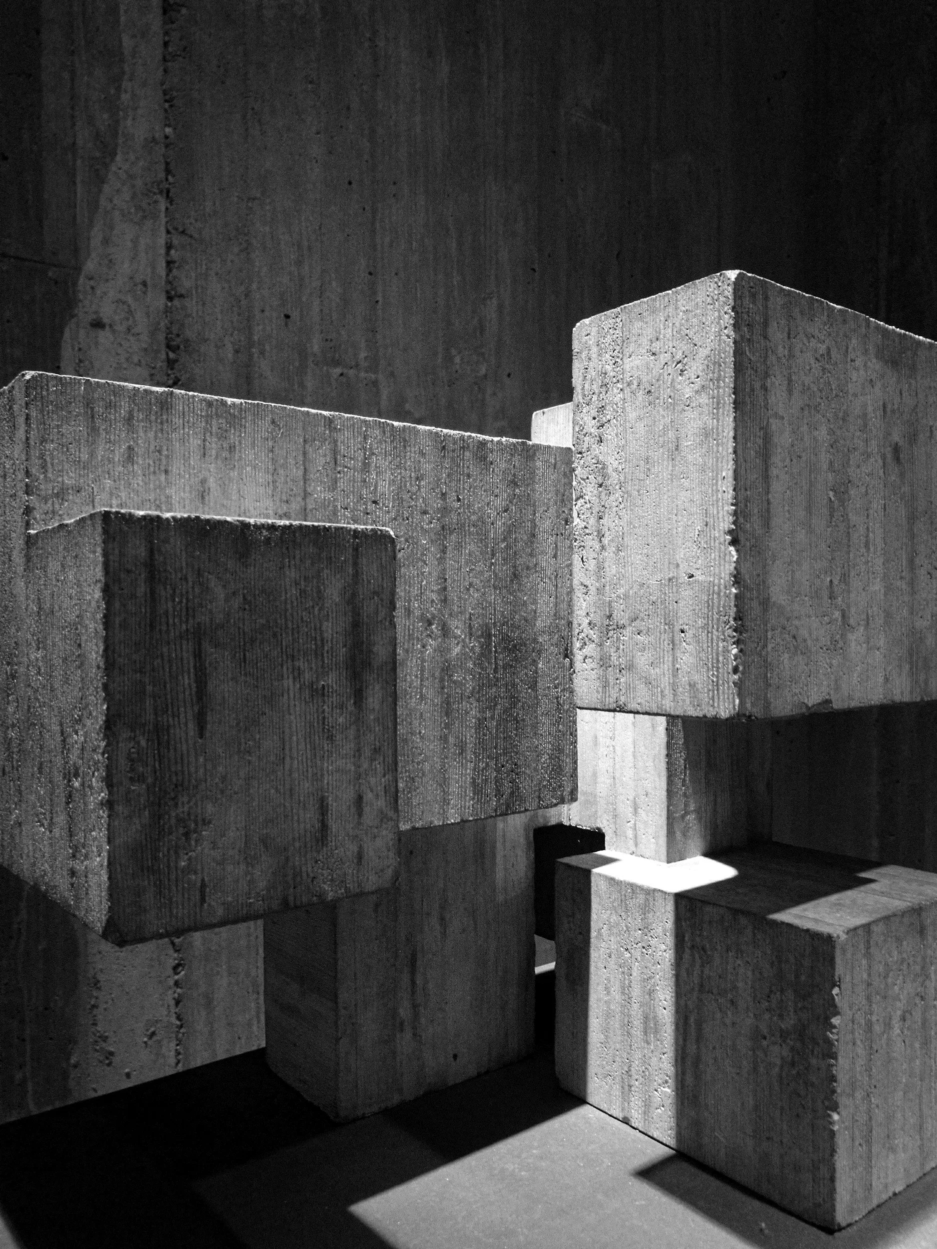 Black and white photo of large concrete blocks arranged in a staggered pattern with shadows cast on the floor.