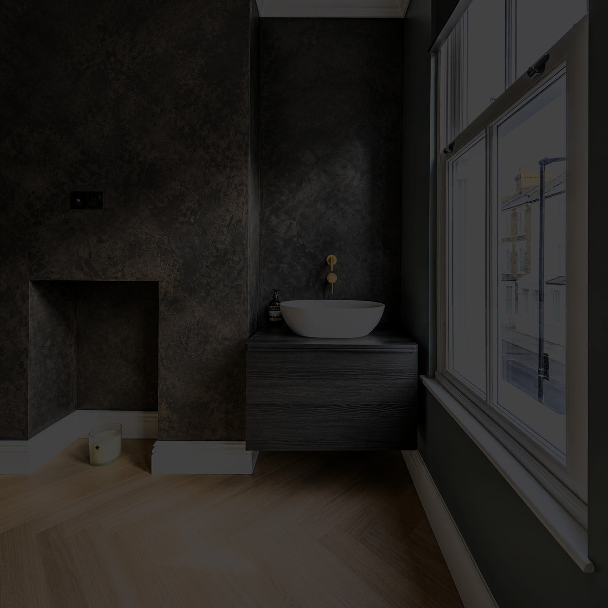 Modern bathroom with dark textured wall, a white vessel sink on a dark wood vanity, a large window with white framing, and a small candle on the light wood floor.