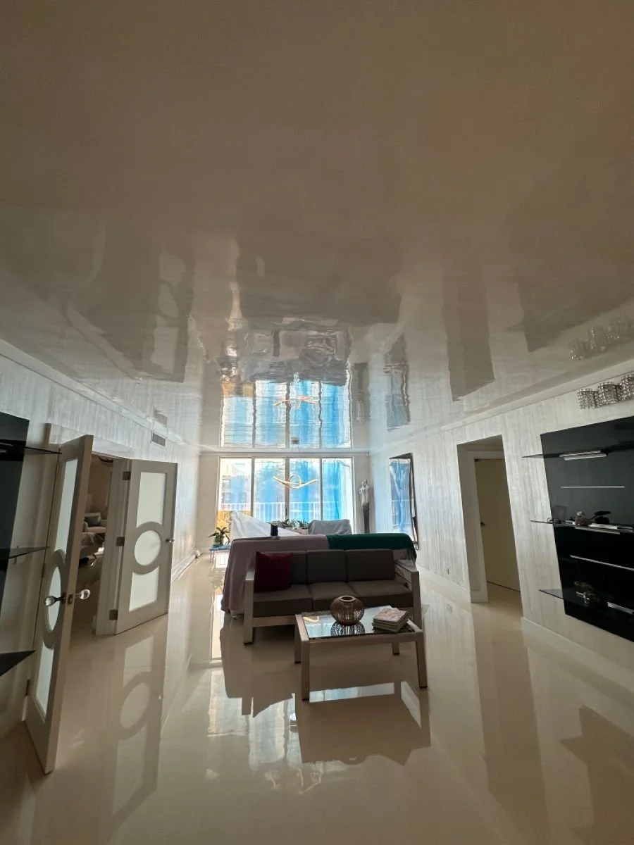 Living room with glossy ceiling, large window, modern furniture, and wall art.
