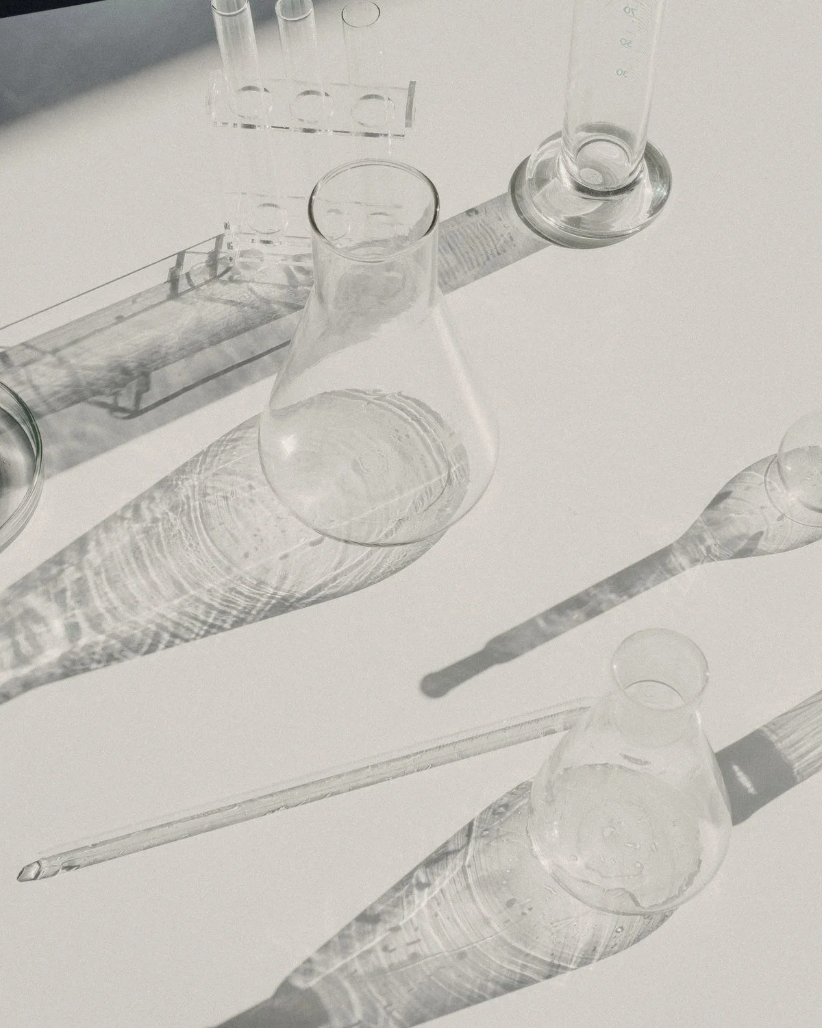 Laboratory glassware casting long shadows on a white bench