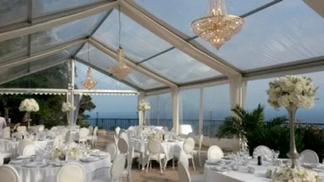Décor de mariage ou réception dans une tente transparente avec chandeliers et fleurs