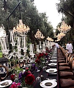 Table de dîner en plein air avec chandeliers et décor floral, préparée pour un événement ou un banquet