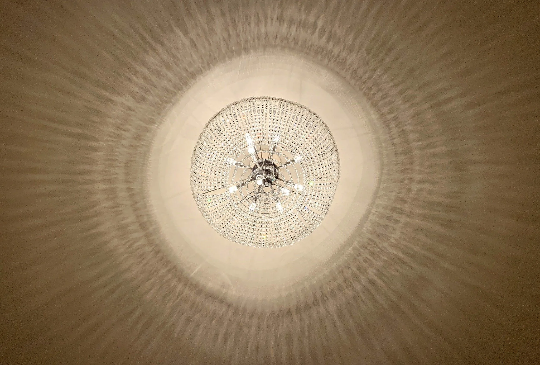 Un lustre en cristal suspendu au plafond, éclairant une pièce et créant des reflets lumineux sur le plafond.