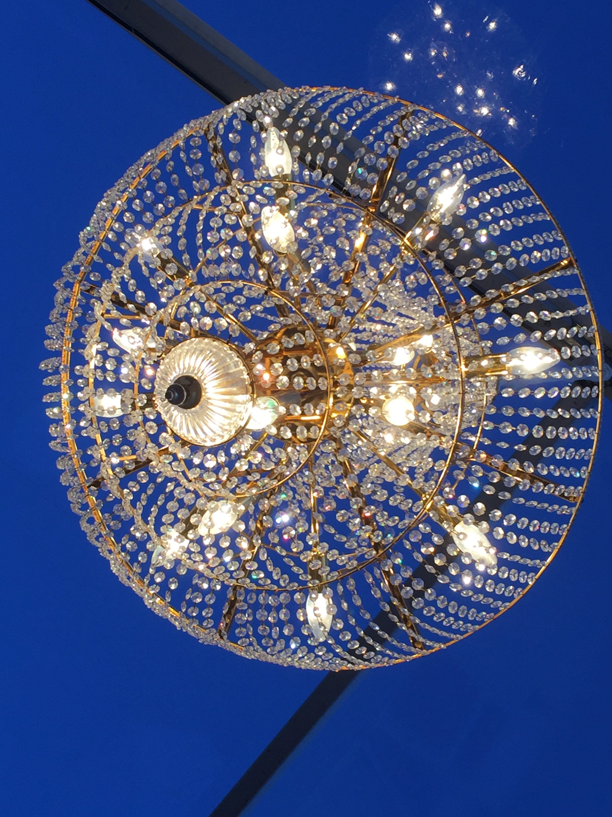 Un lustre décoratif en forme de coquillage orné de cristaux brillants, suspendu dans un ciel bleu nocturne.