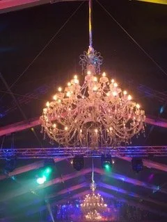 Un lustre en cristal suspendu au plafond dans une pièce éclairée colorée.
