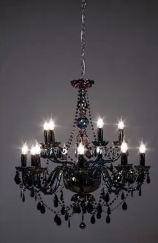 Un chandelier en cristal avec plusieurs ampoules allumées suspendu au plafond.