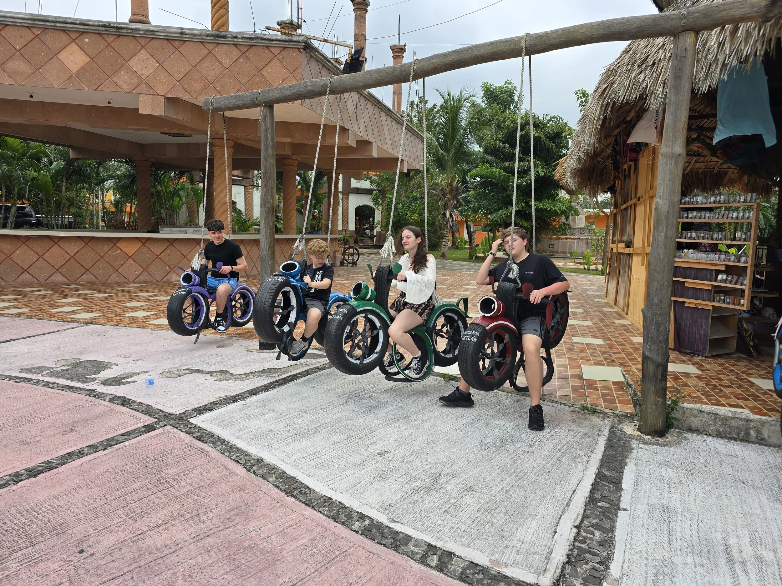 Four kids sitting on a 4-person bike swing in Cozumel, Mexico