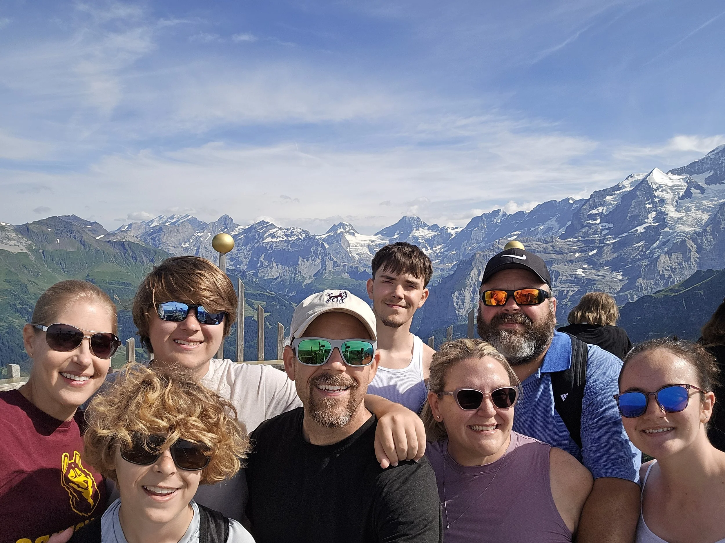 Eight smiling faces with the view of the Swiss alps behind them
