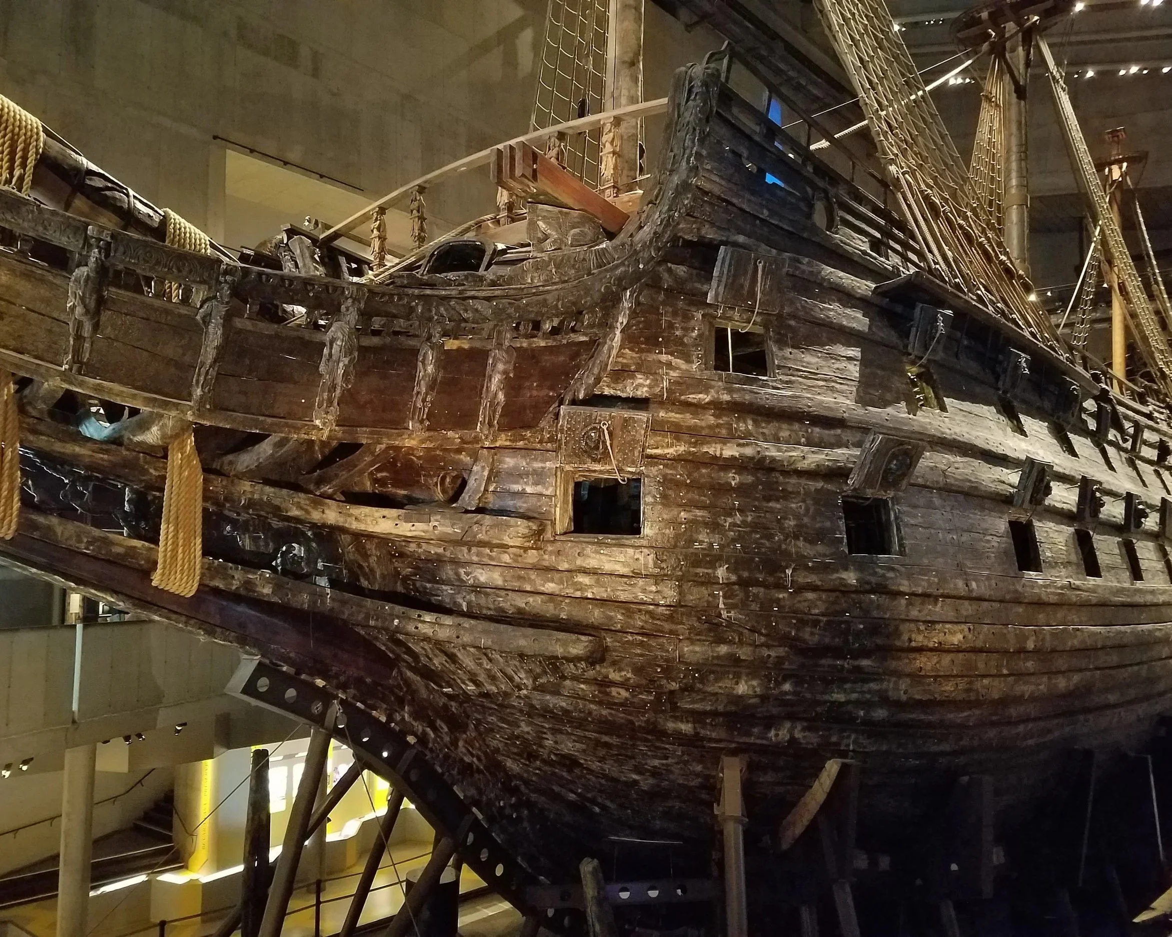 An indoor exhibit of a large, historic wooden sailing ship with multiple masts and rigging, displayed at a museum.