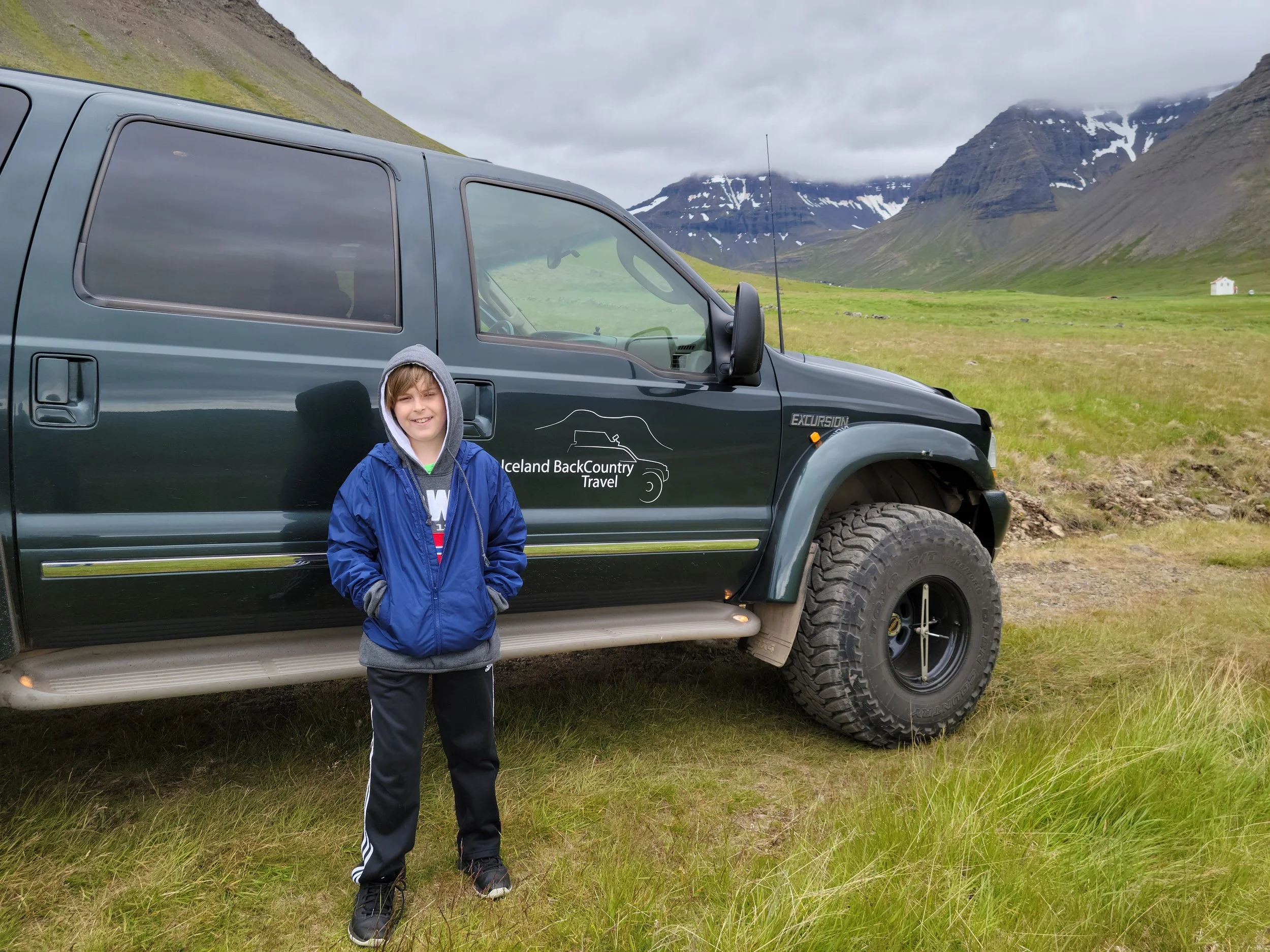 A young child excited to go on an outdoor adventure tour in a Ford Excursion vehicle during a family vacation.