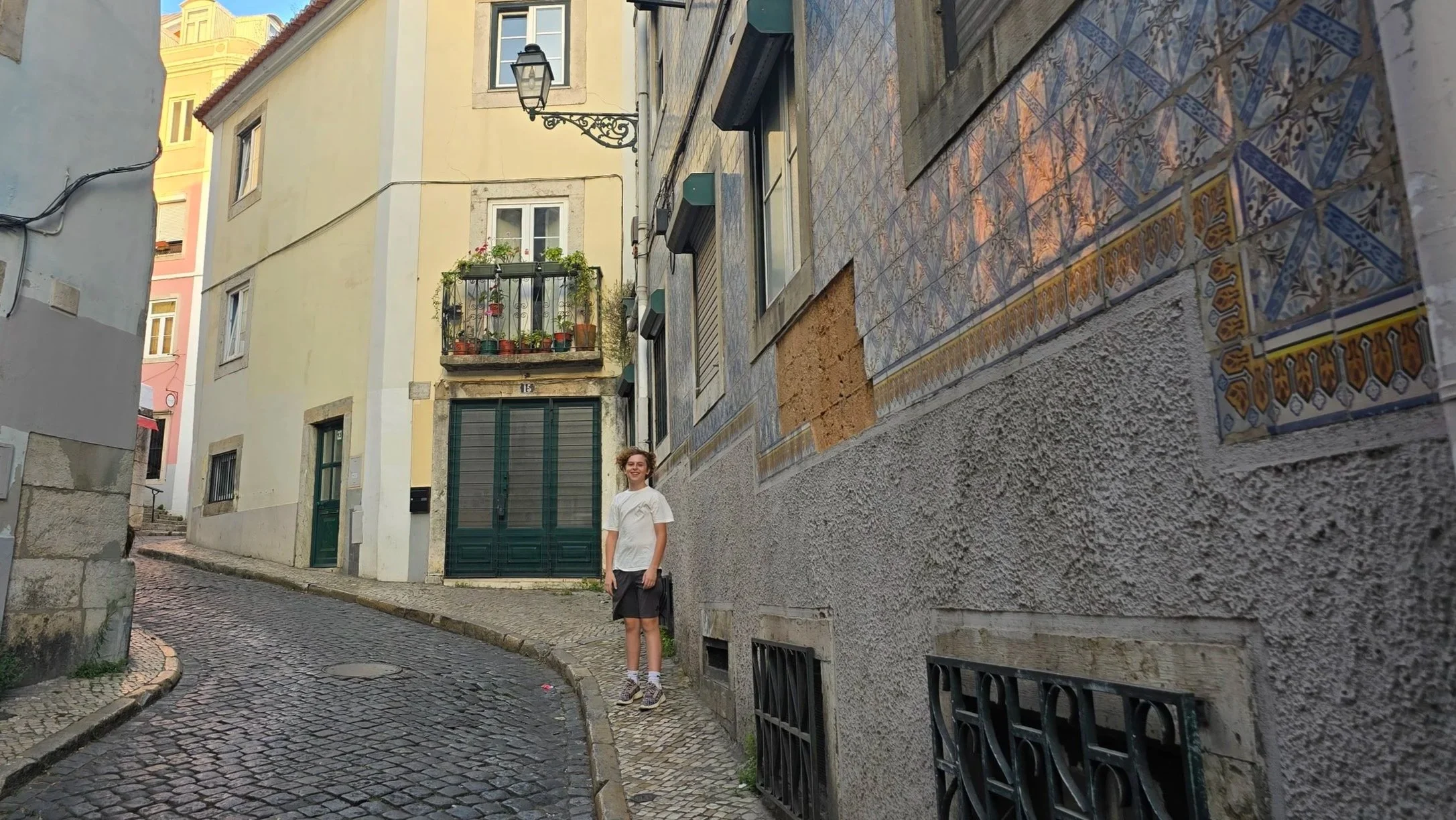 Logan standing on narrow cobblestoned sidewalk with a narrow cobblestone street