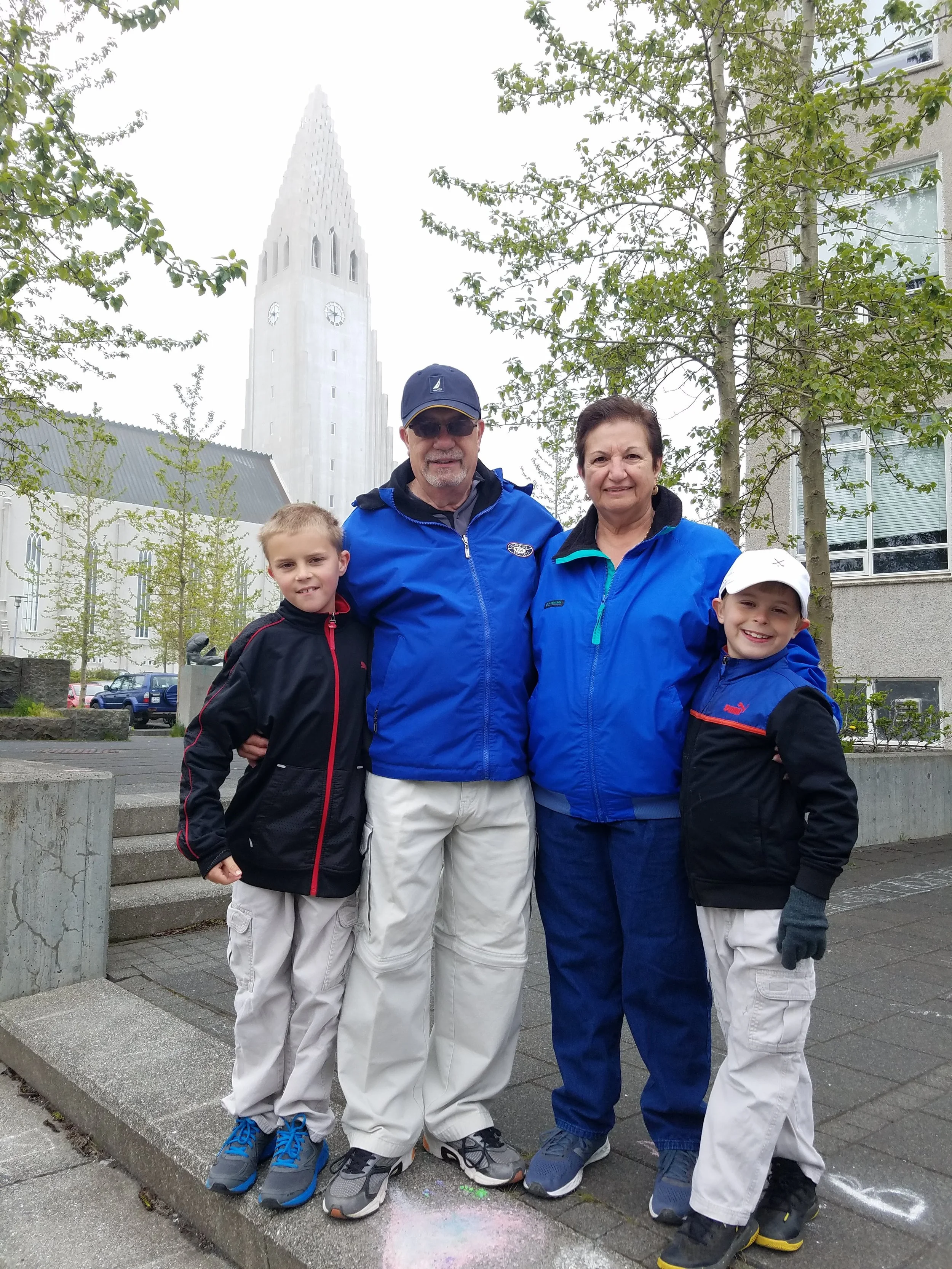 Grandparents with their two grandchildren standing together in front of Hallgrímskirkja church in Reykjavik, Iceland.