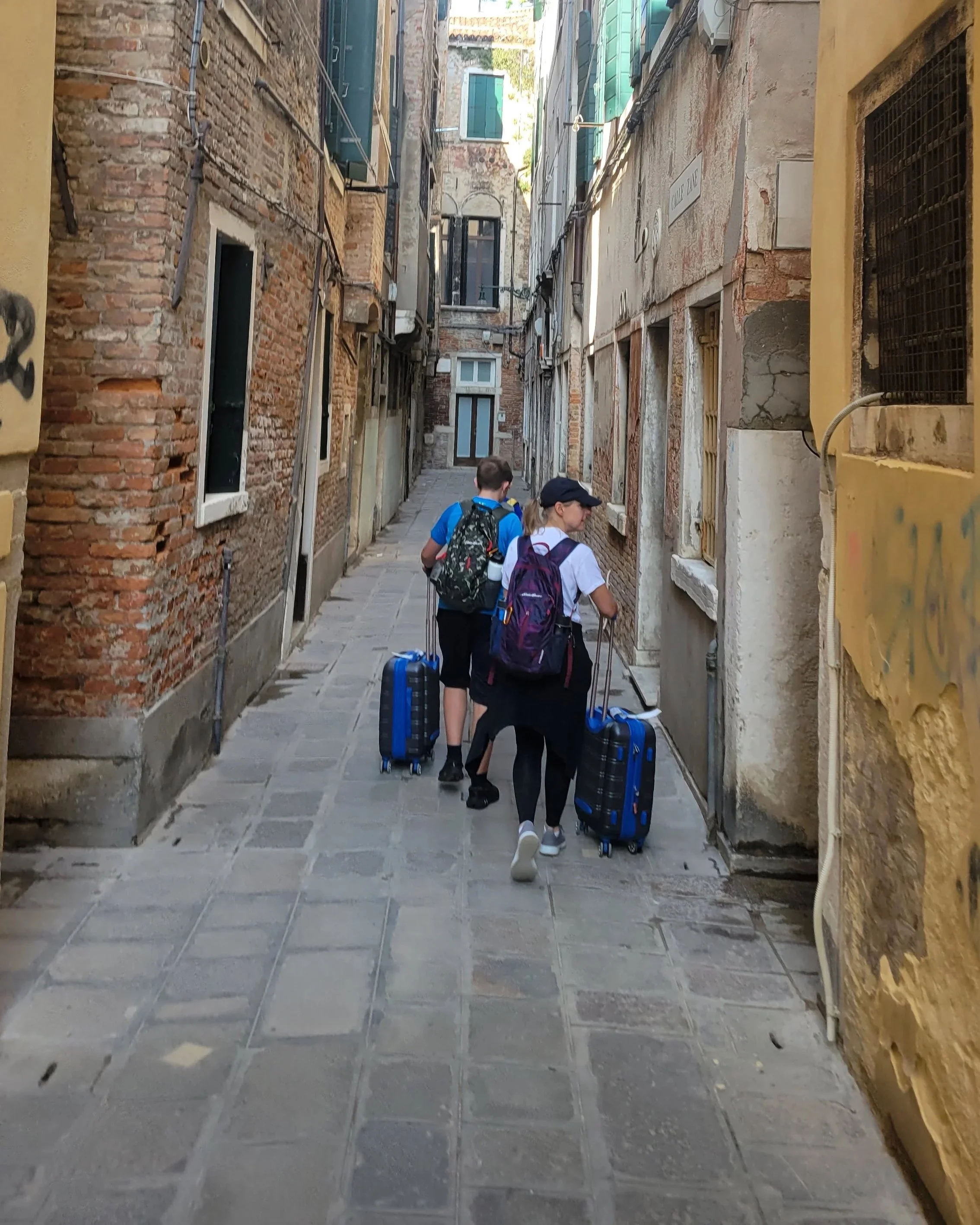 Small family with luggage on cobblestone street in Venice, Italy