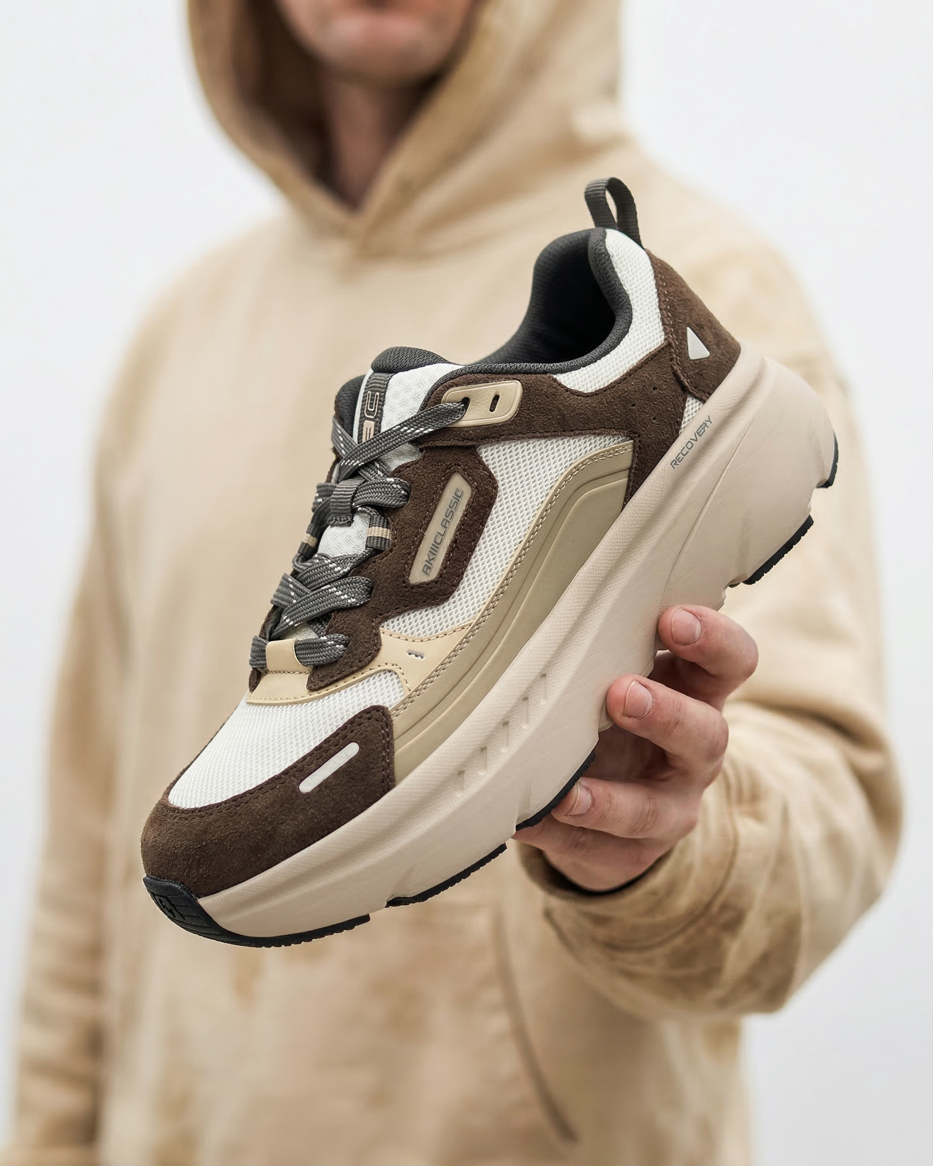 akiii-classic-recovery-sneaker-brown-beige-hand-hold-lifestyle-white-bg-01.png