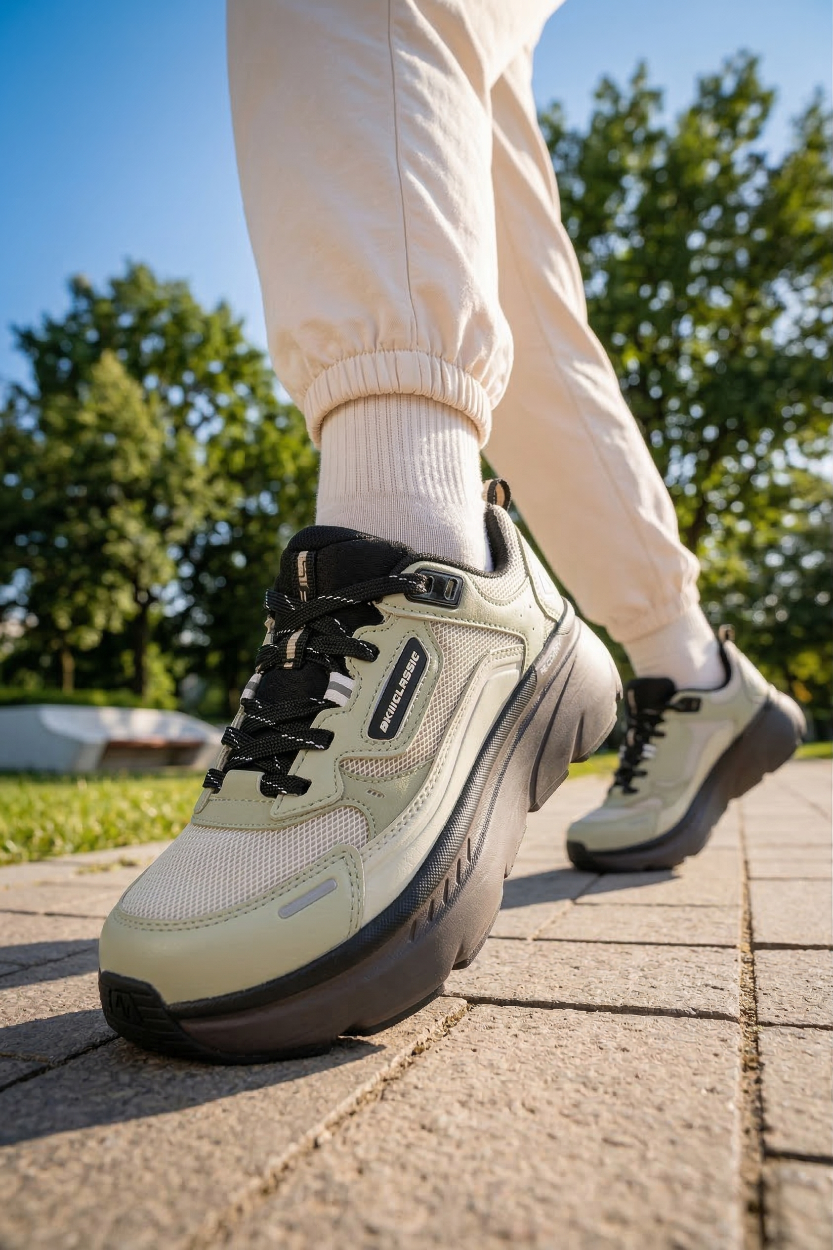 akiii-classic-recovery-sneaker-olive-green-on-foot-walking-pavement-park-front-01.png
