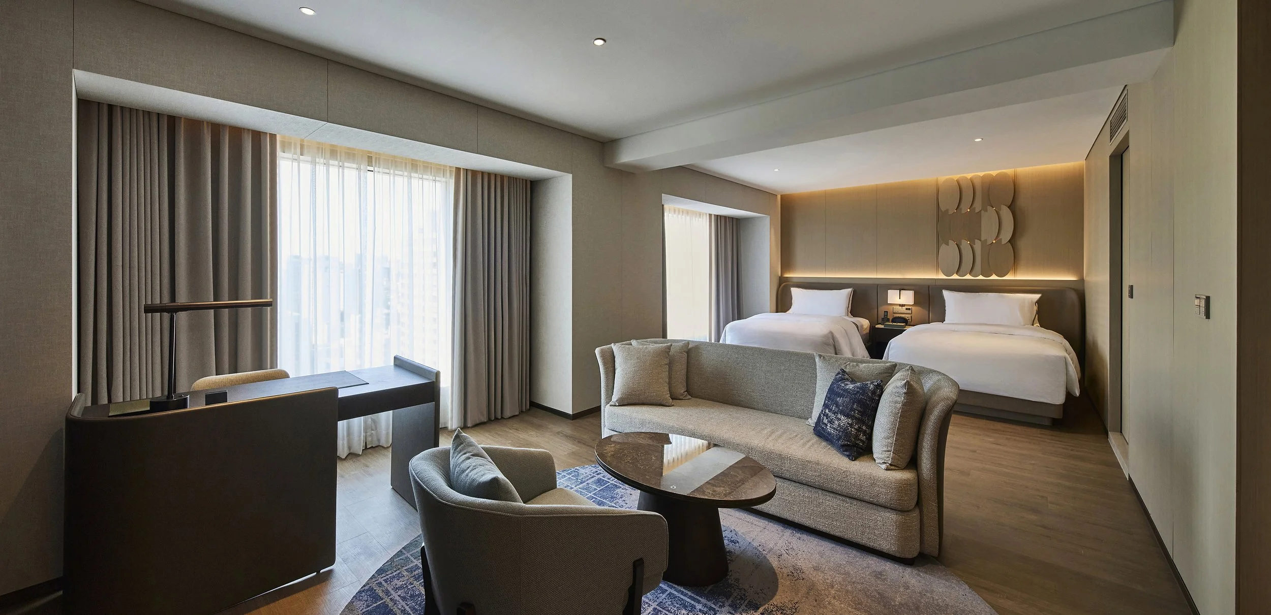 luxury-hotel-junior-suite-twin-bedroom-ambient-beige-circle-headboard-sofa-02.jpg