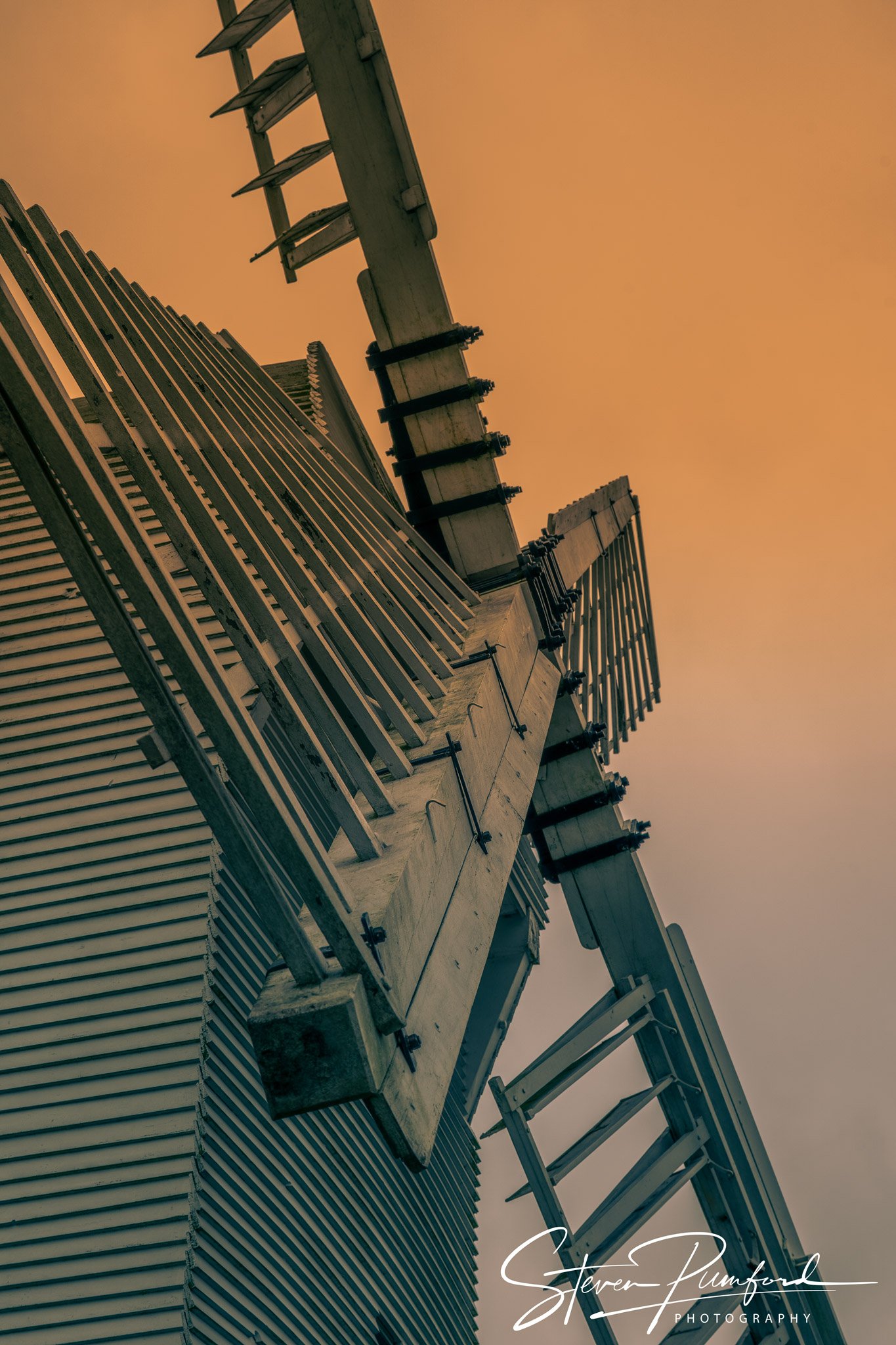 Construction site with a building under construction, showing scaffolding and wooden structures, against a sunset sky.