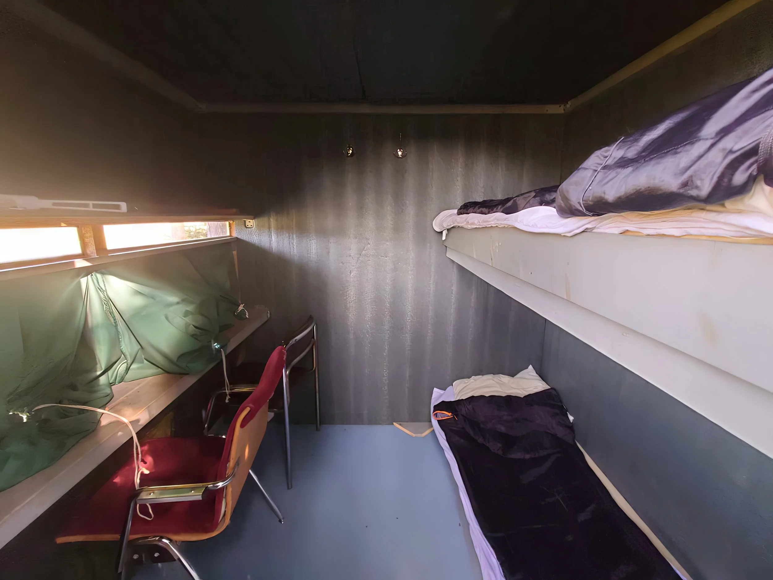Interior of a small wildlife photography hide in the Finnish wilderness with bunk beds, camera openings and sleeping bags prepared for an overnight stay