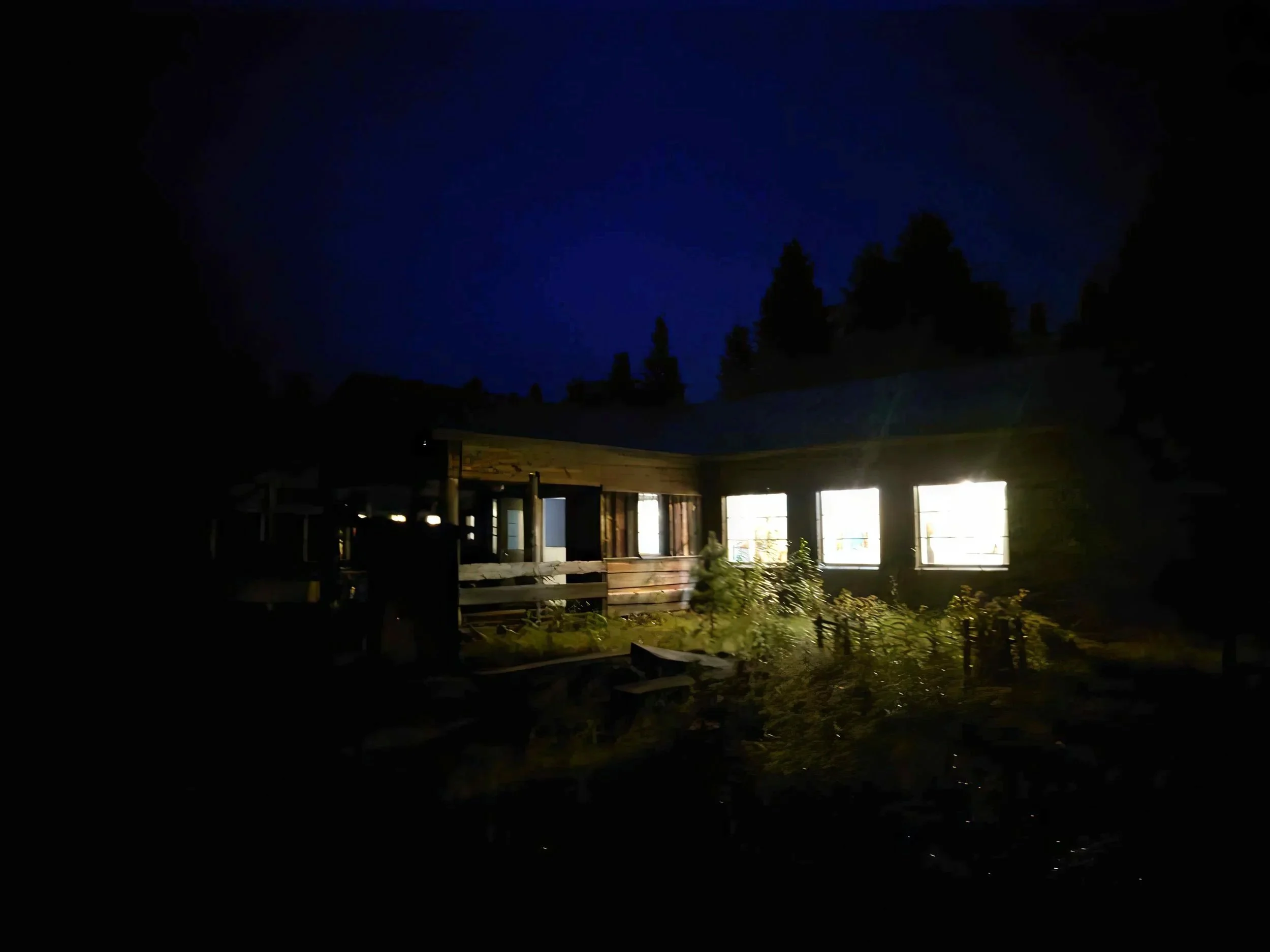 The lodge at Kuhmo Bear Centre at night, with light coming out from within, lighting up the dark.