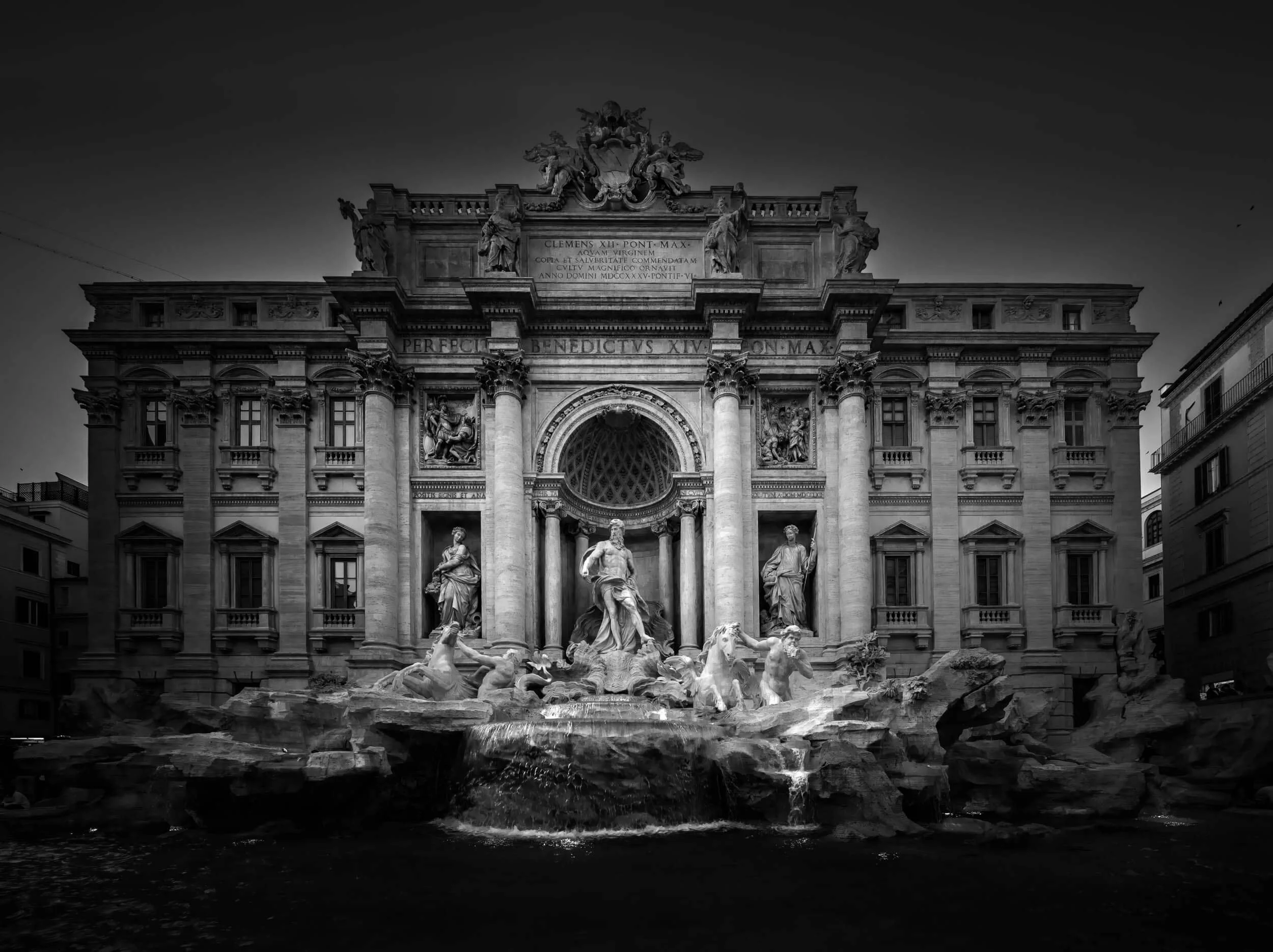 Black and white photo of a historic architectural building with detailed sculptures and a fountain in front.