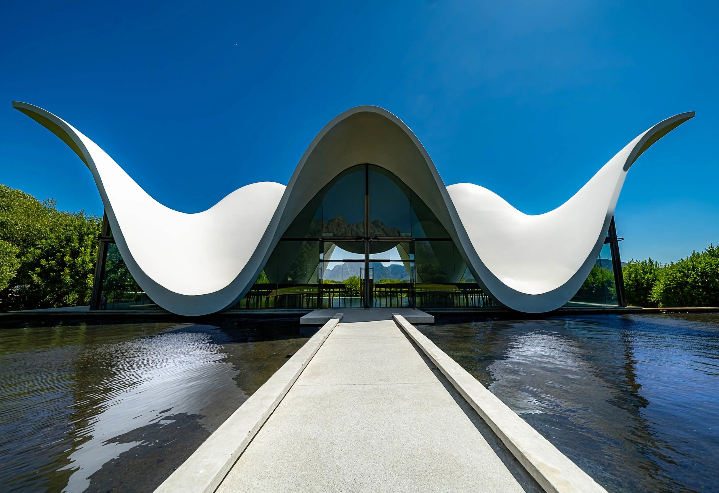 The Milwaukee Art Museum with its distinctive wing-like architecture, reflected in the surrounding water on a bright sunny day.