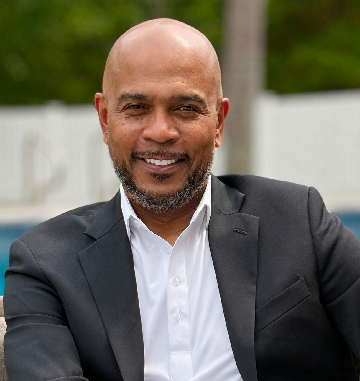 Author Hughes A. Robinson III seated outdoors in a black suit and white shirt.