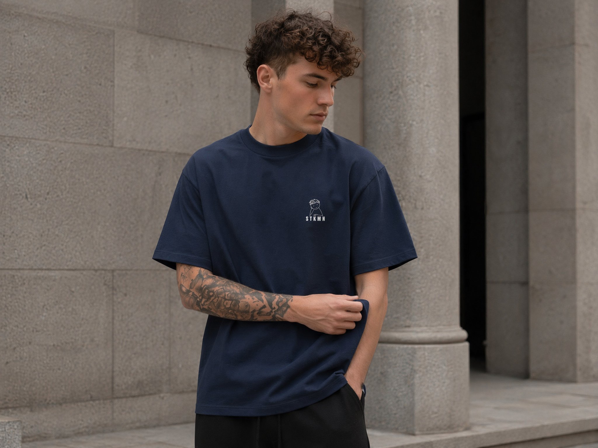 Model wearing the STKMN Essential Tee in navy with a relaxed oversized fit.
