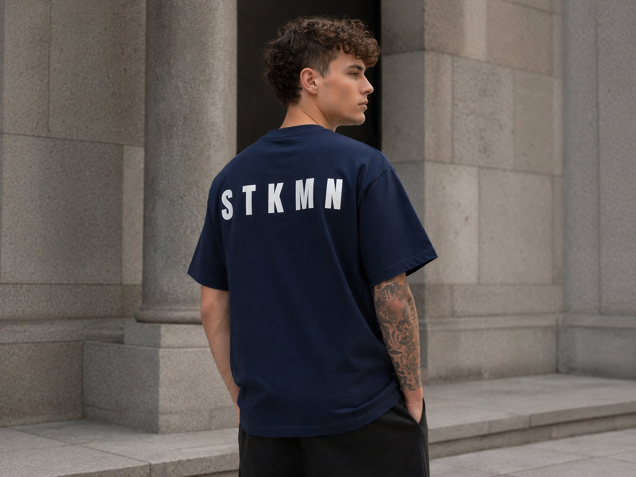 Model wearing the STKMN Essential Tee in navy with a relaxed oversized fit.