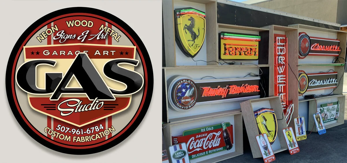 Display of various neon and painted signs for automotive brands, drinks, and logos at a sign and art shop.