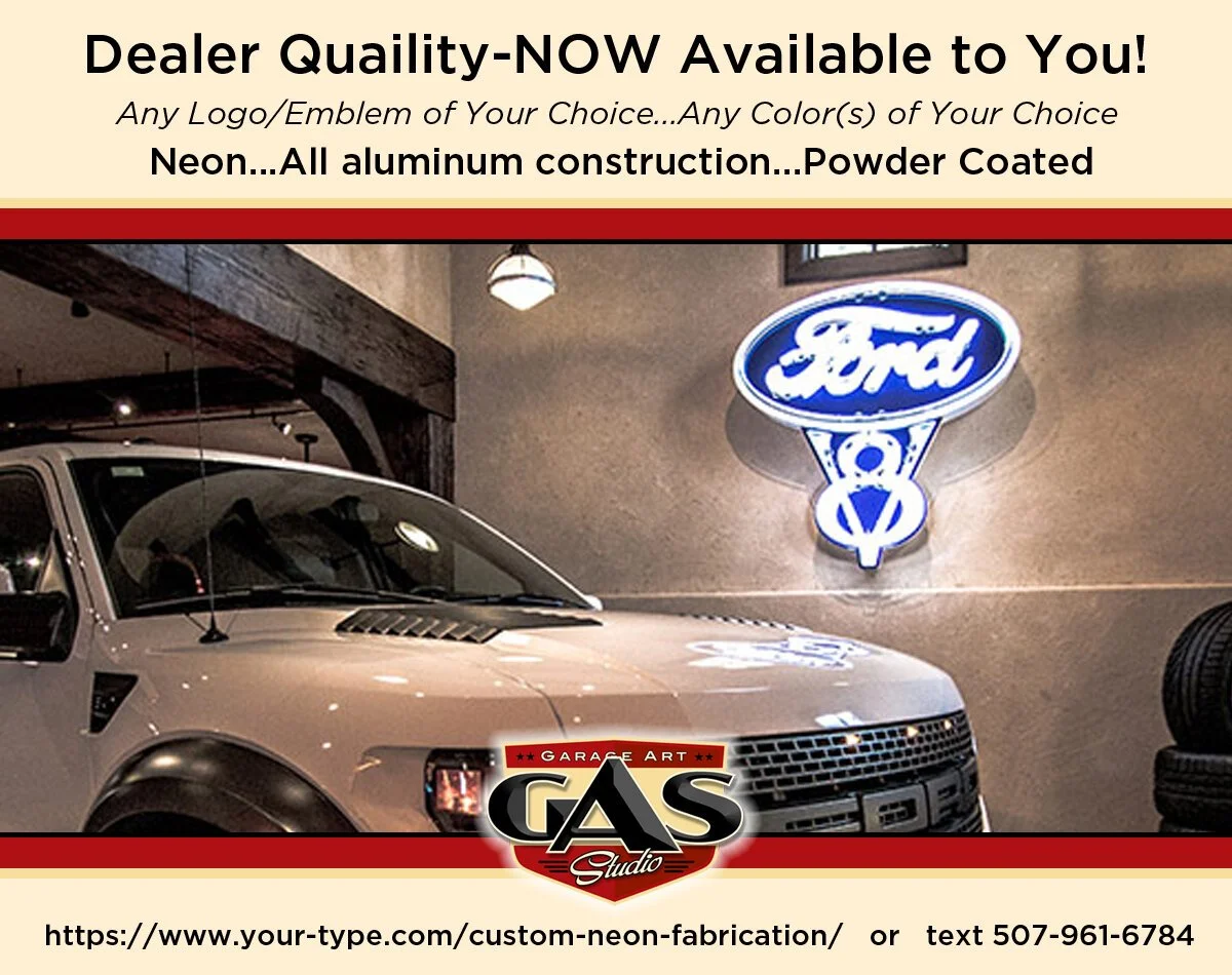 Advertisement for custom neon car badges by Garage Art Gas Studio, featuring a Ford logo badge illuminated with neon on a beige wall, with a gray pickup truck in the foreground.