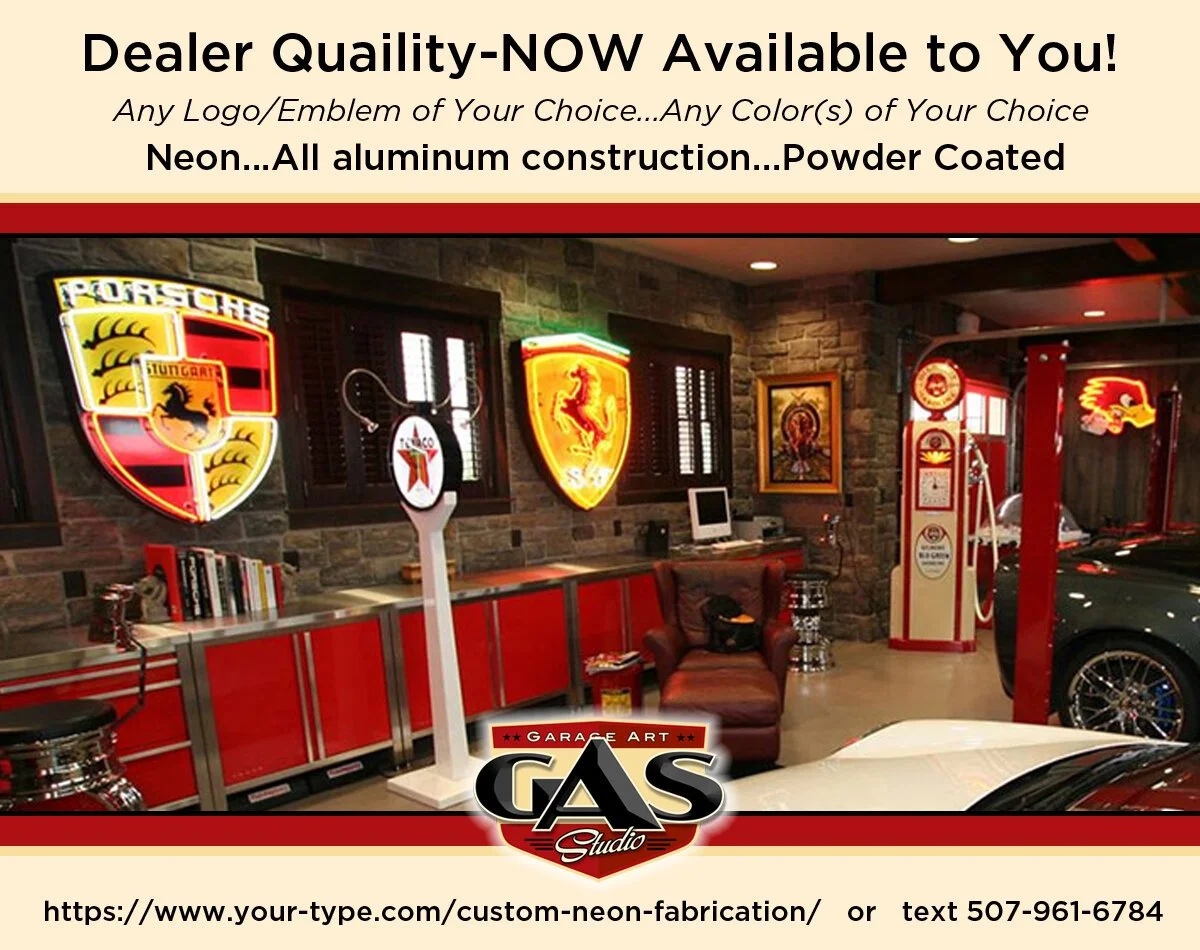 Interior of a garage decorated with neon signs of Porsche, Ferrari, and other automotive logos, featuring red cabinetry, a leather chair, retro-style advertising machines, and partially visible cars.